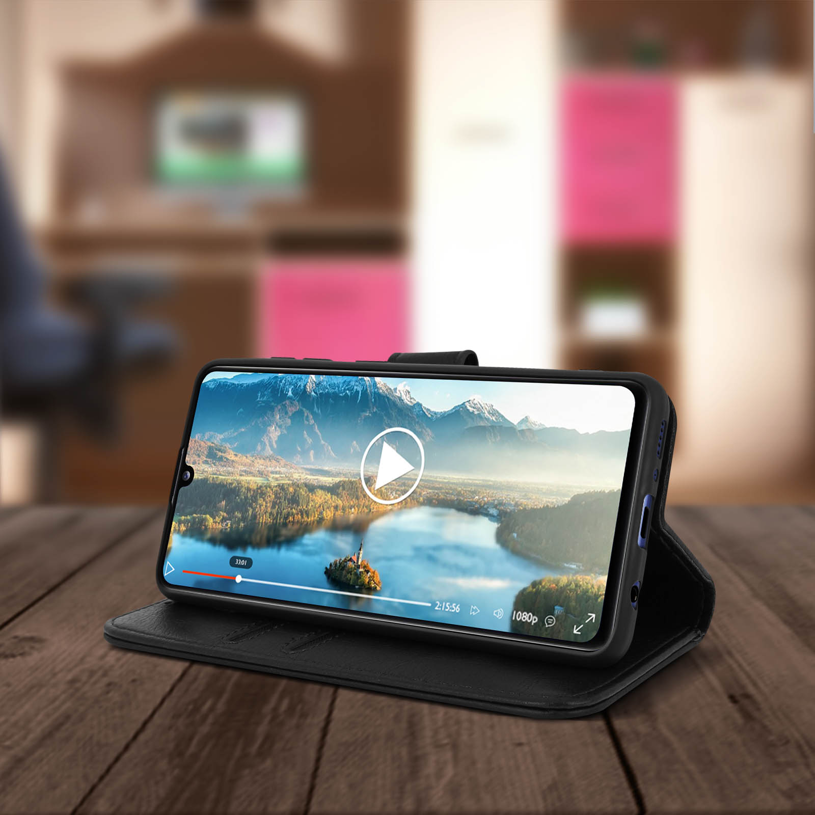 Een telefoon met een video, in een zwarte hoes, op een houten tafel, met een wazige achtergrond.