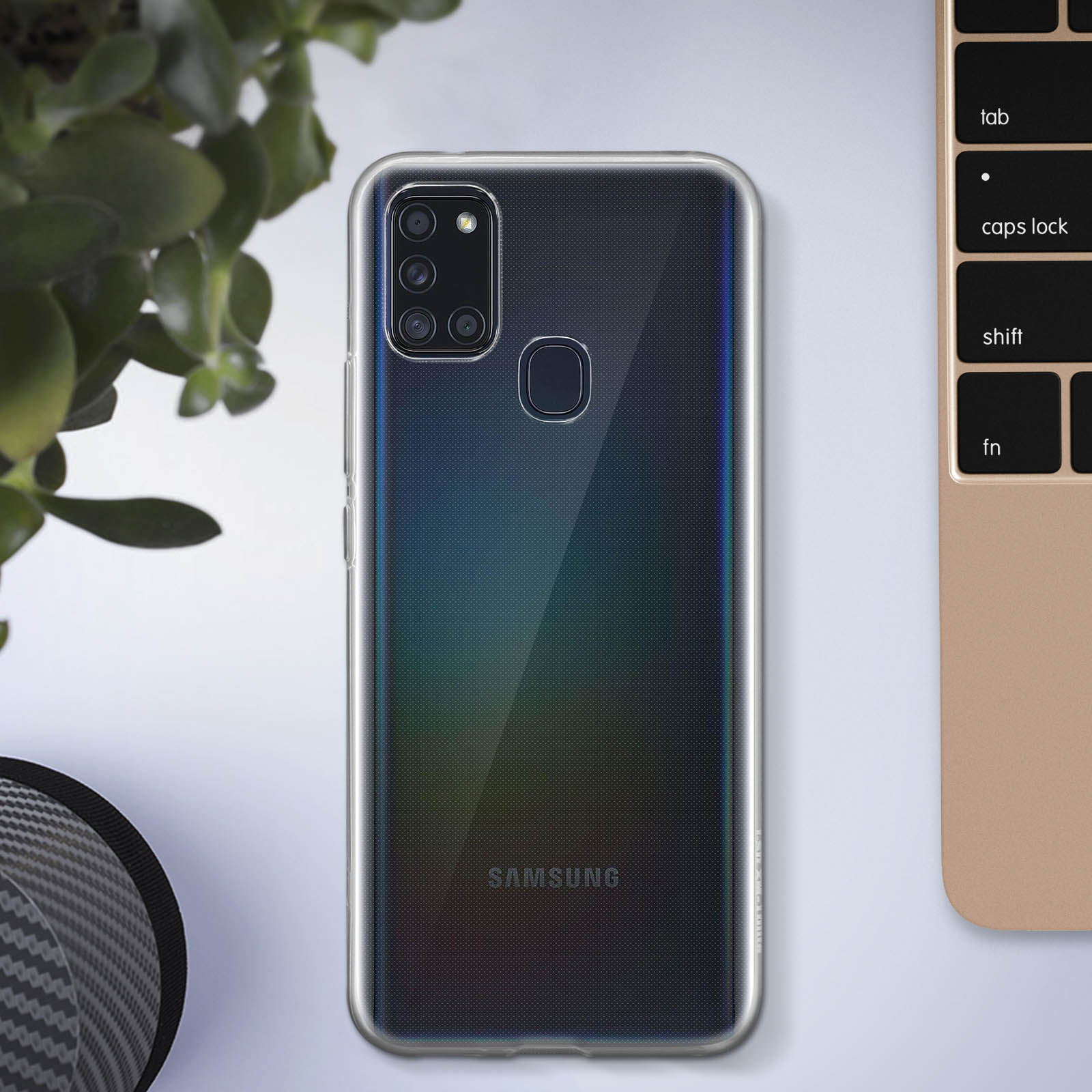 Una custodia trasparente per telefono su un telefono, accanto a una tastiera. Il telefono ha un retro sfumato scuro con il logo Samsung.