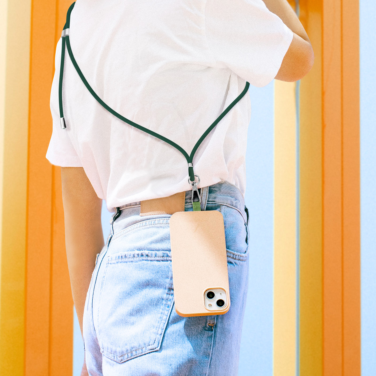 Una persona indossa una maglietta bianca e jeans con un laccetto per telefono verde scuro.