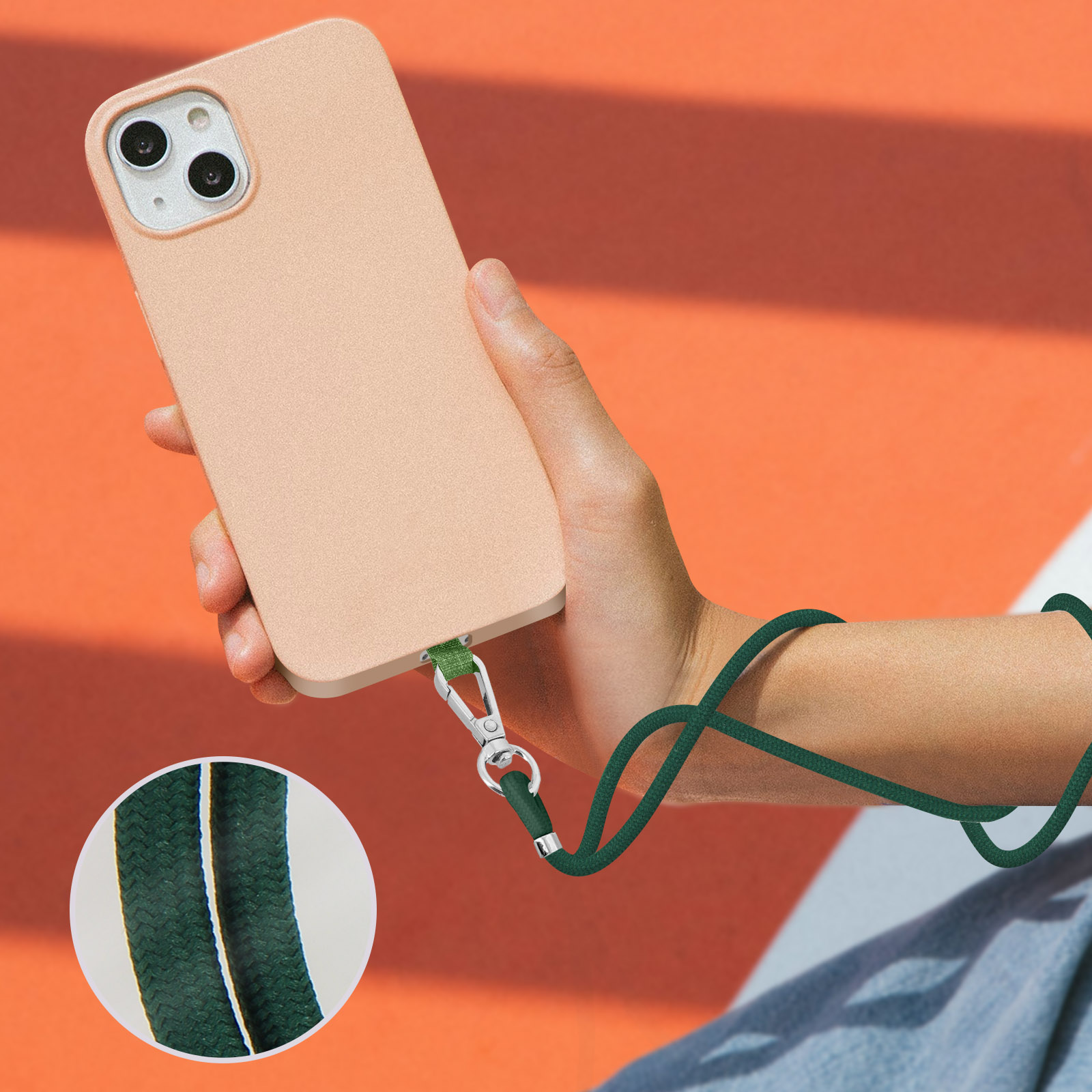 Una mano tiene un telefono color pesca con un cordino verde attaccato in basso.