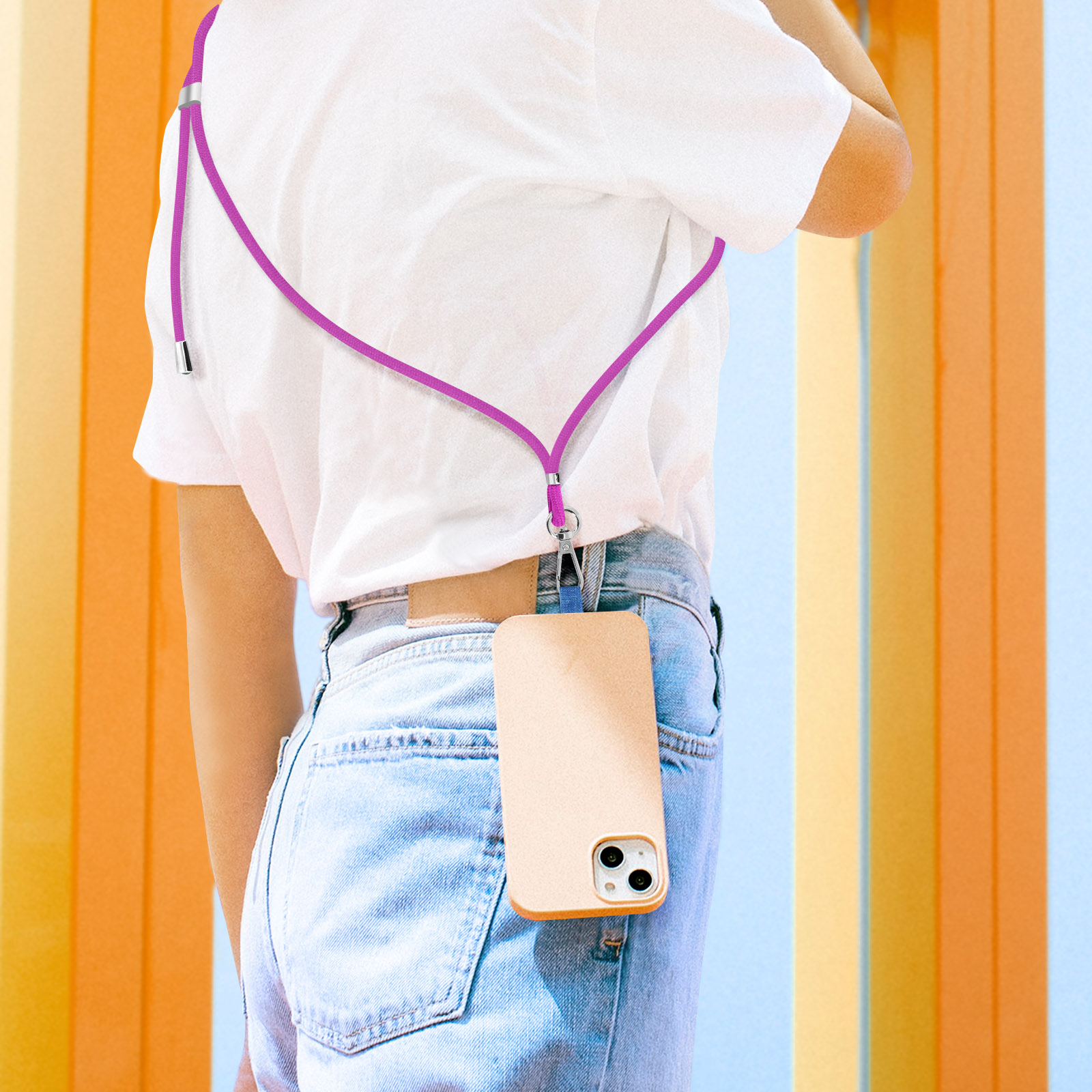 Una persona indossa una t-shirt bianca e jeans blu con un laccetto rosa per telefono e una custodia beige.