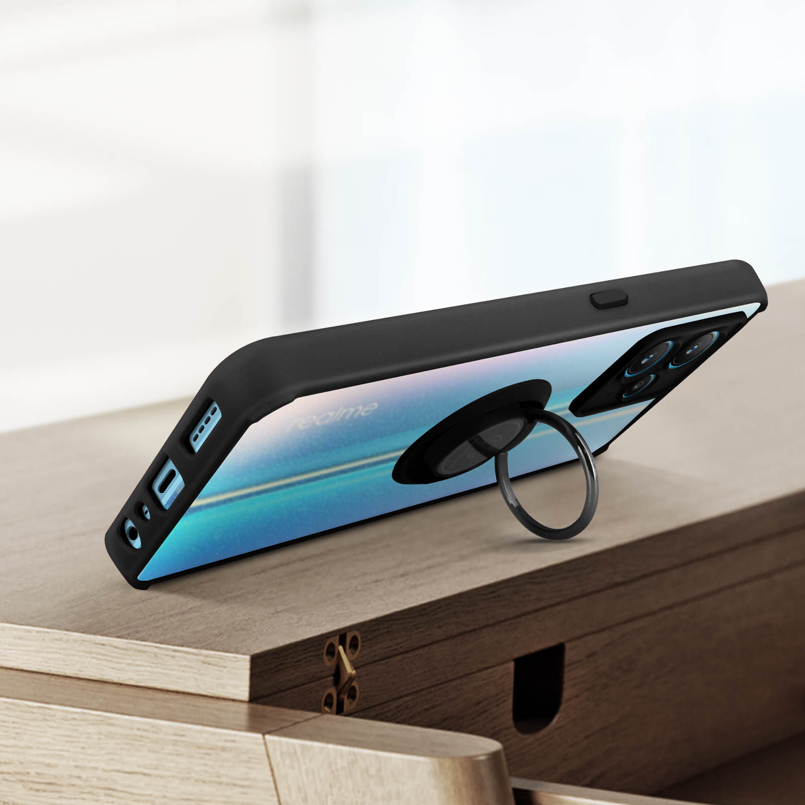 Telefoon met een zwarte hoes en ringhouder, op een houten oppervlak.