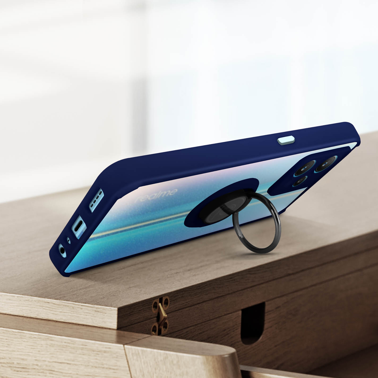 Coque de téléphone bleu marine avec support anneau, sur une surface boisée.
