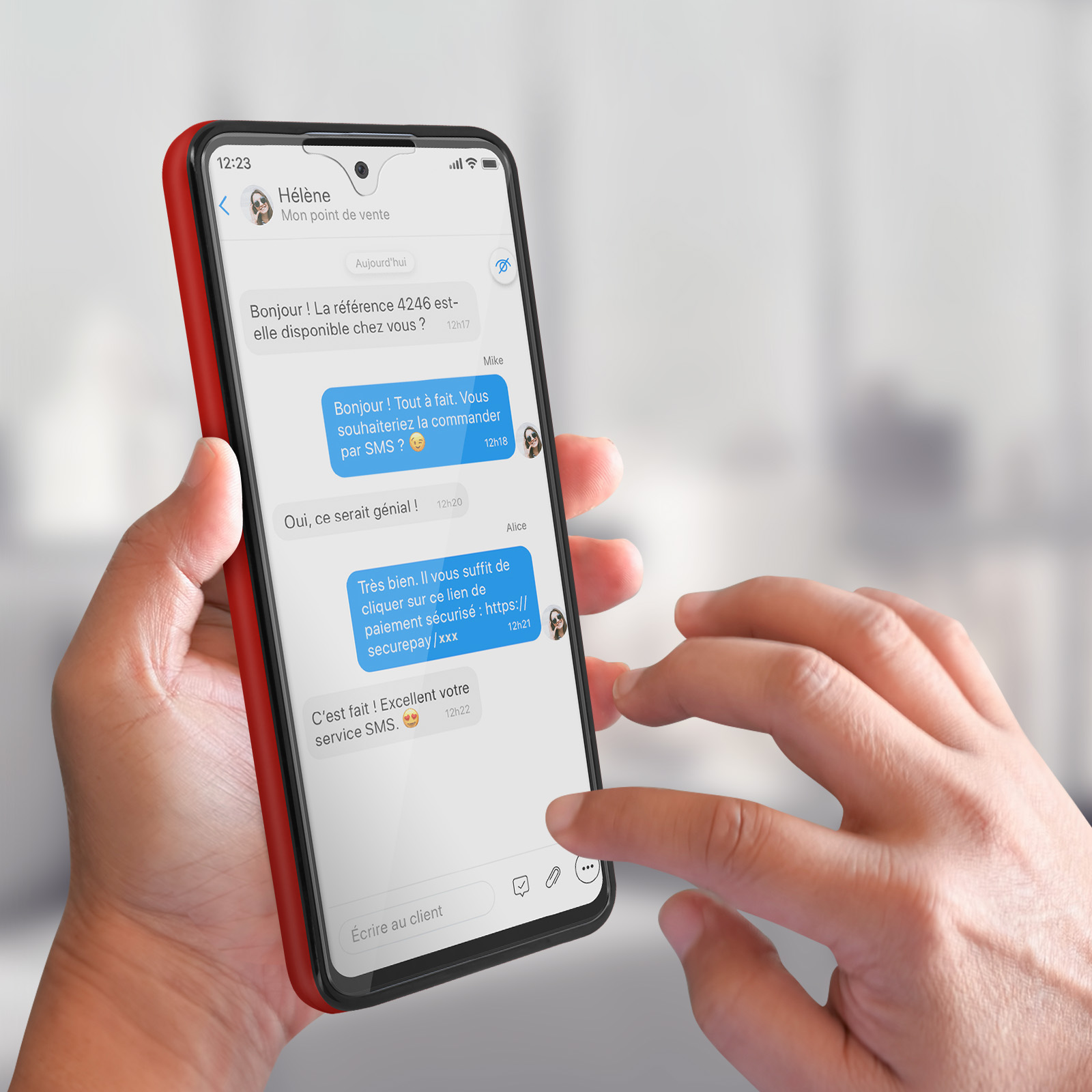 Une personne tient un téléphone avec une coque rouge. L'écran affiche une conversation de chat.