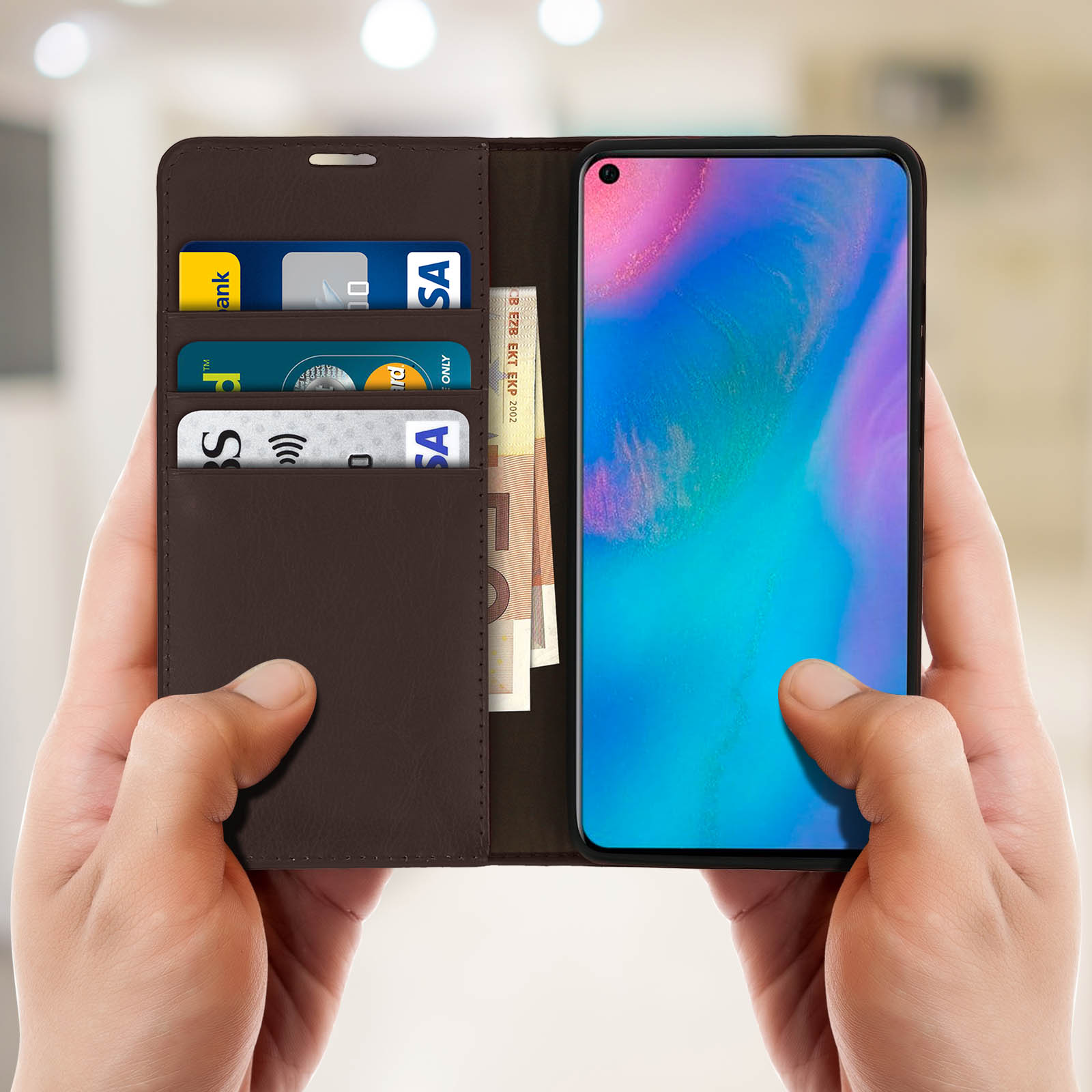 Telefono in una custodia di pelle marrone, con carte e denaro. Mani che lo tengono. Sfondo sfocato.