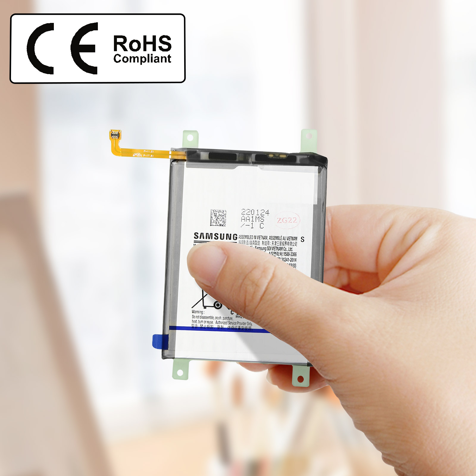 Une main tenant une batterie de téléphone. La batterie a des étiquettes et un connecteur.