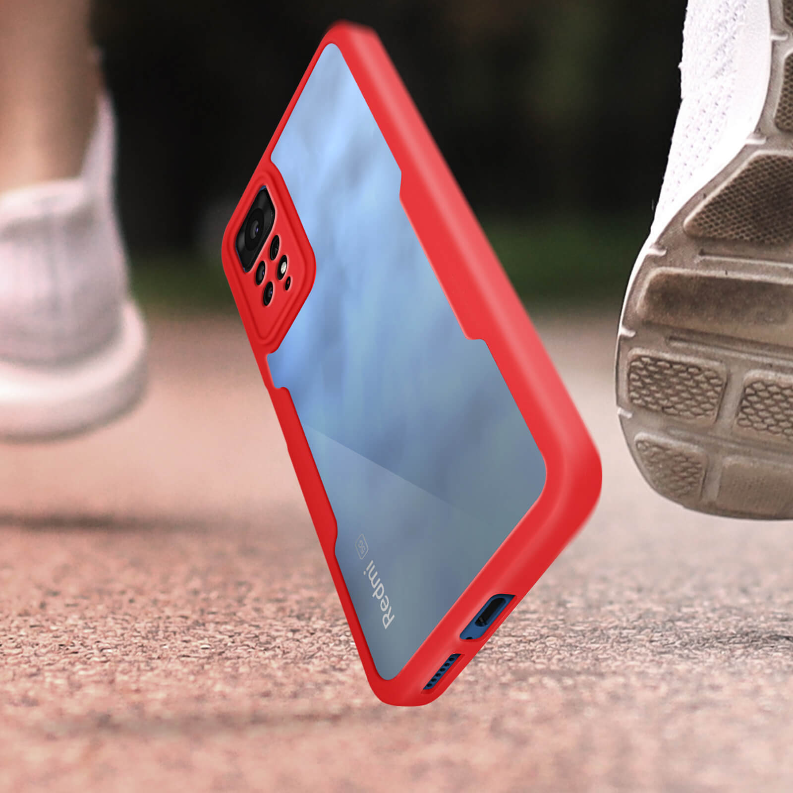 Custodia rossa per telefono in movimento, accanto a una scarpa da corsa. Custodia trasparente, cornice rossa.