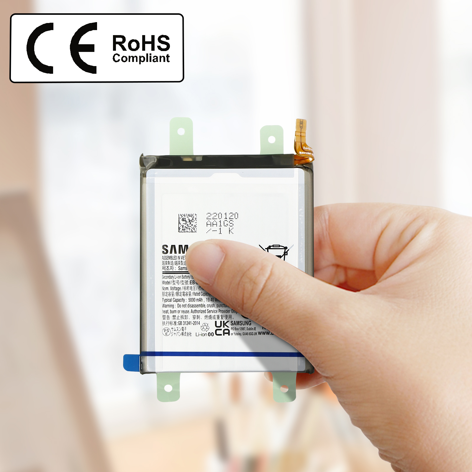 Une main tenant une batterie de téléphone, avec les étiquettes CE et RoHS en arrière-plan.