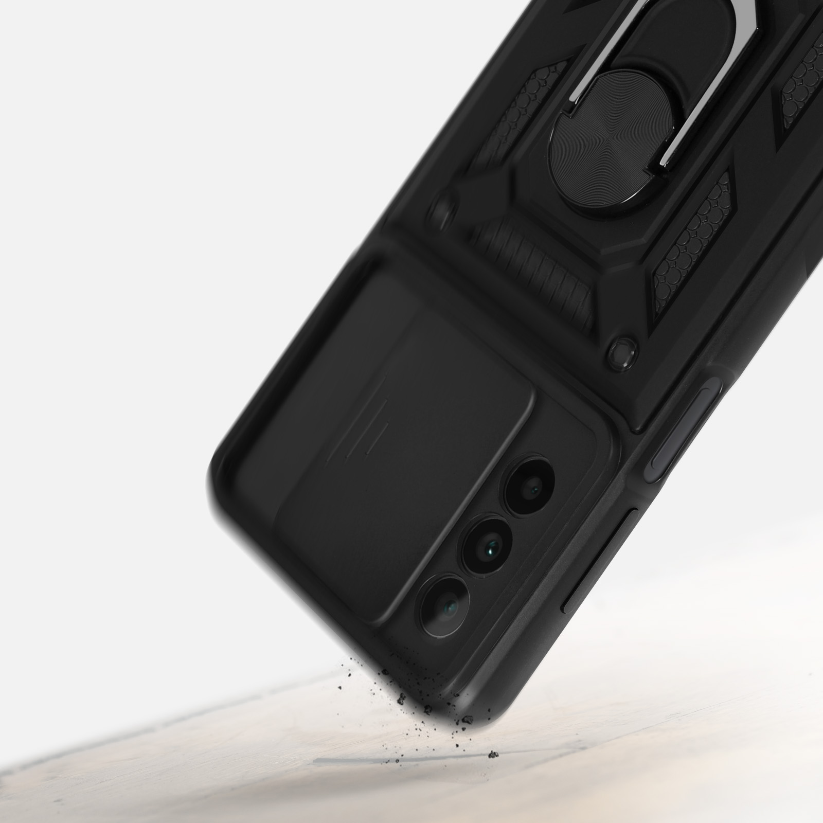 Custodia per telefono nera con porta anello. La custodia è angolata, con particelle di polvere in primo piano.