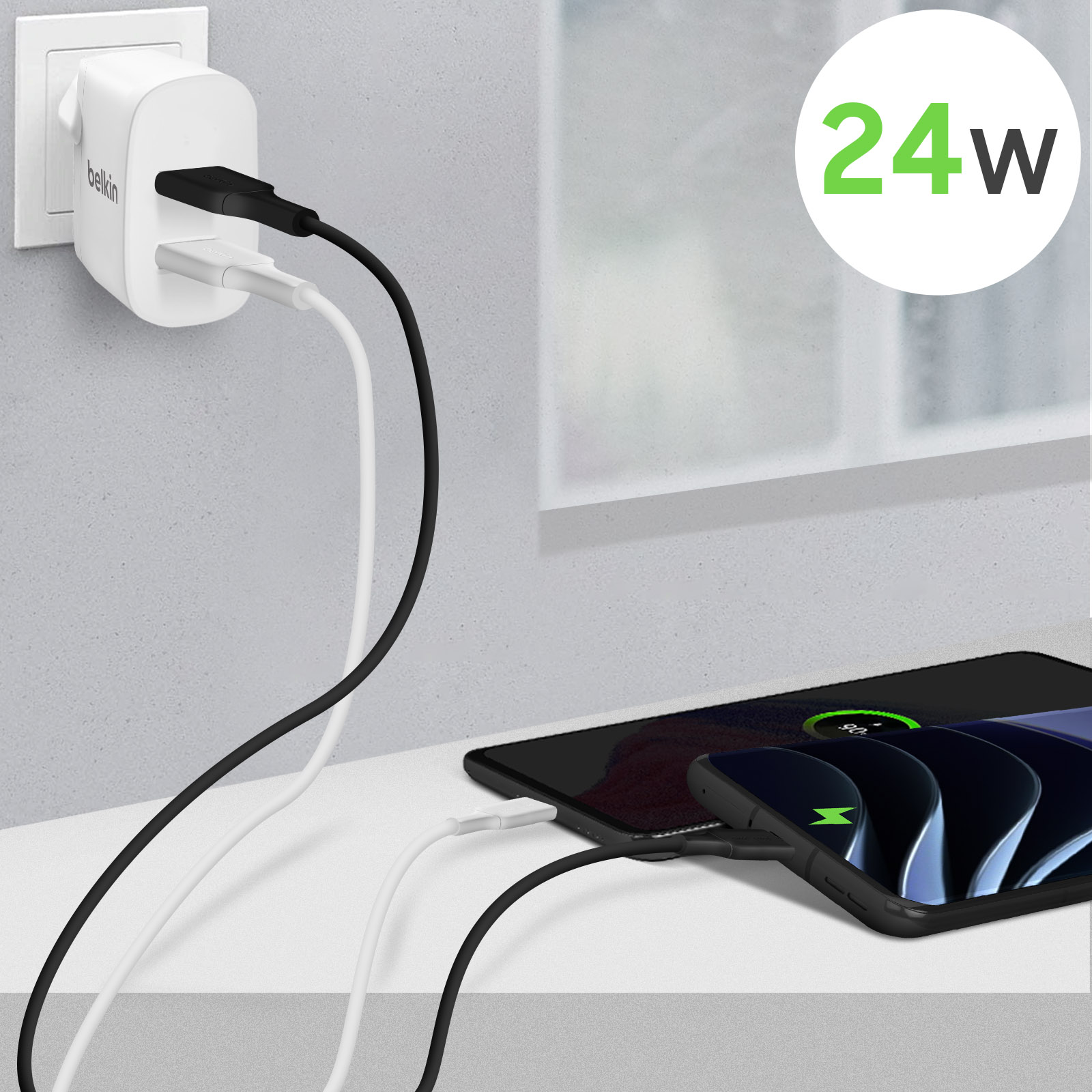Un telefono in carica con due cavi collegati a un caricatore Belkin, che mostra 24W.