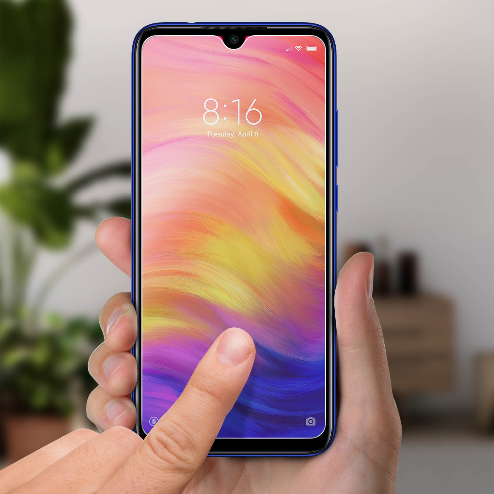 Una mano tocca lo schermo di un telefono che mostra un display colorato. Il telefono ha una cornice blu.
