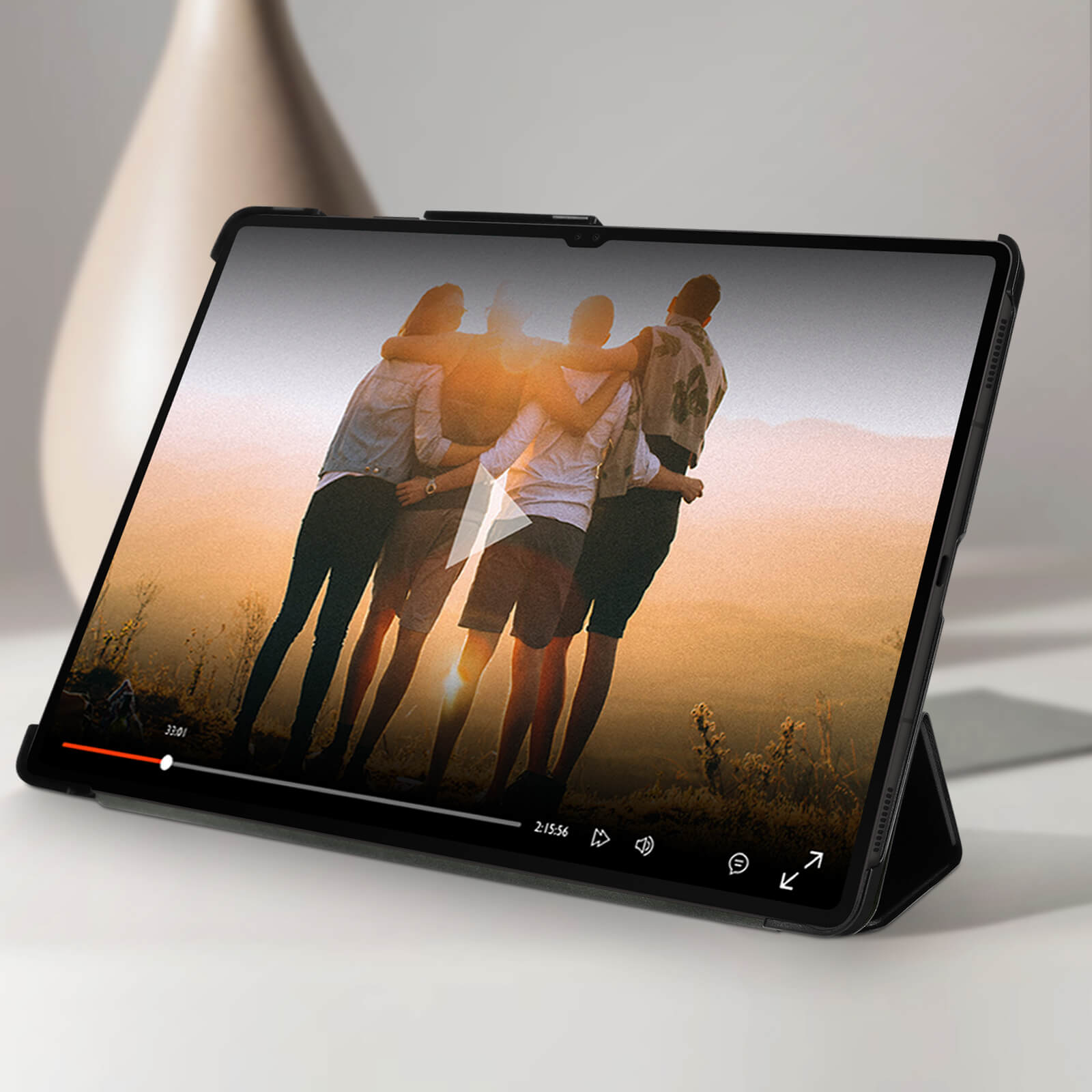 Un tablet che mostra un video. Le persone si abbracciano. Un vaso è sullo sfondo.