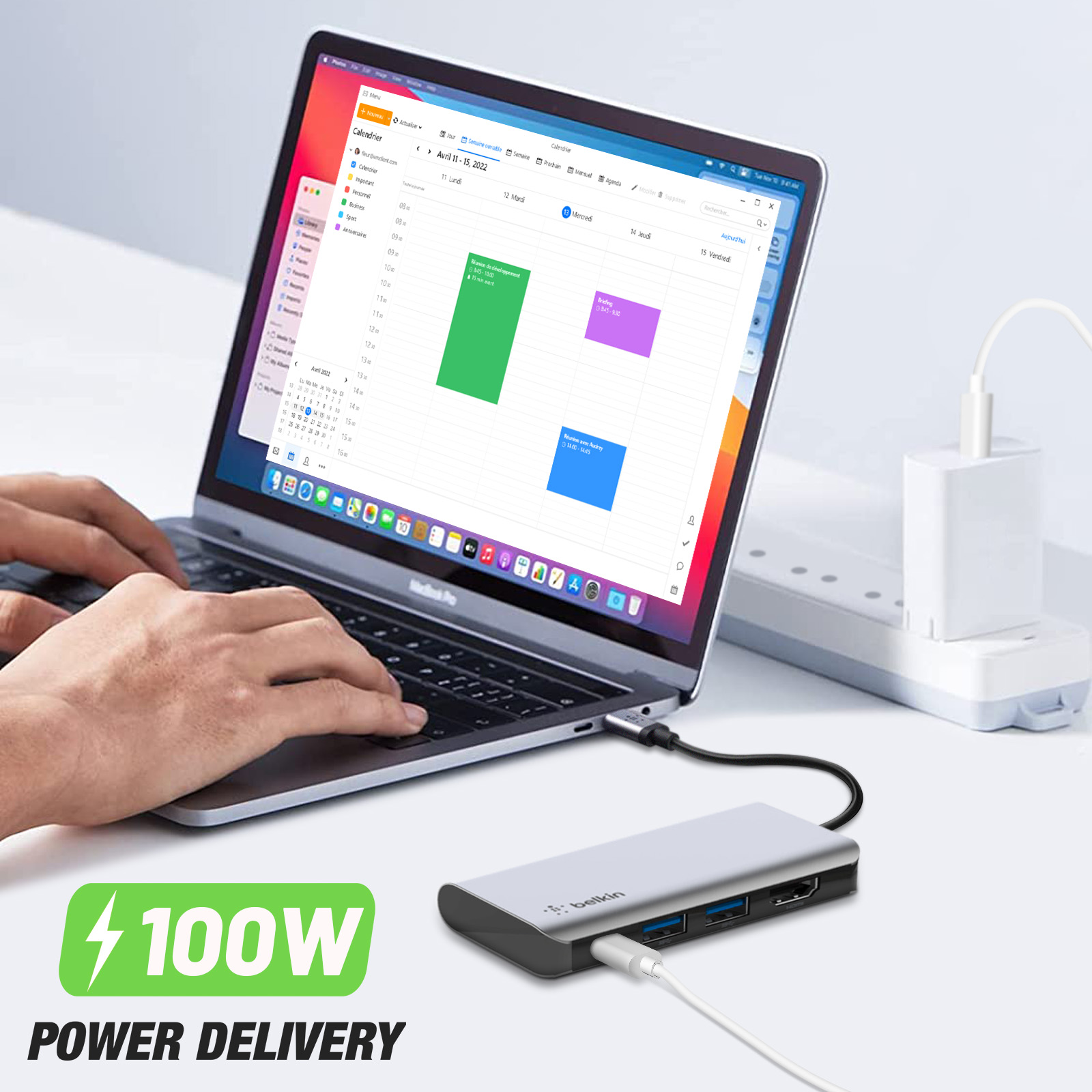 Laptop che mostra un calendario, con un hub Belkin e un adattatore di alimentazione. Su una scrivania.