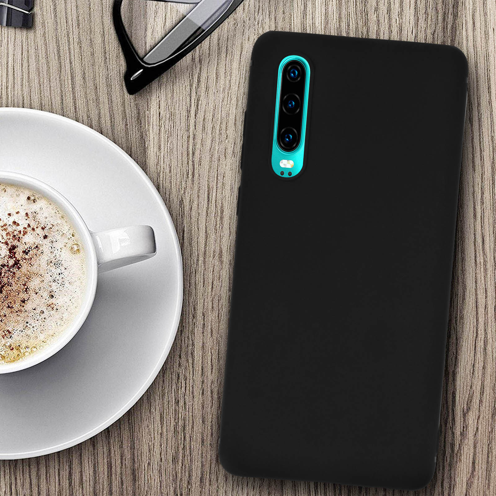 Custodia nera per telefono su tavolo di legno. Tazza di caffè e occhiali vicini.