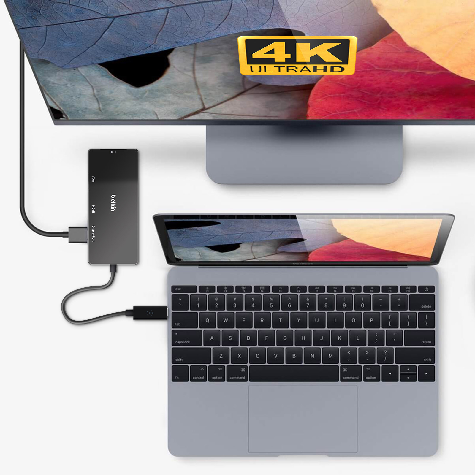 Laptop collegato a un adattatore Belkin con un display e una TV dietro.