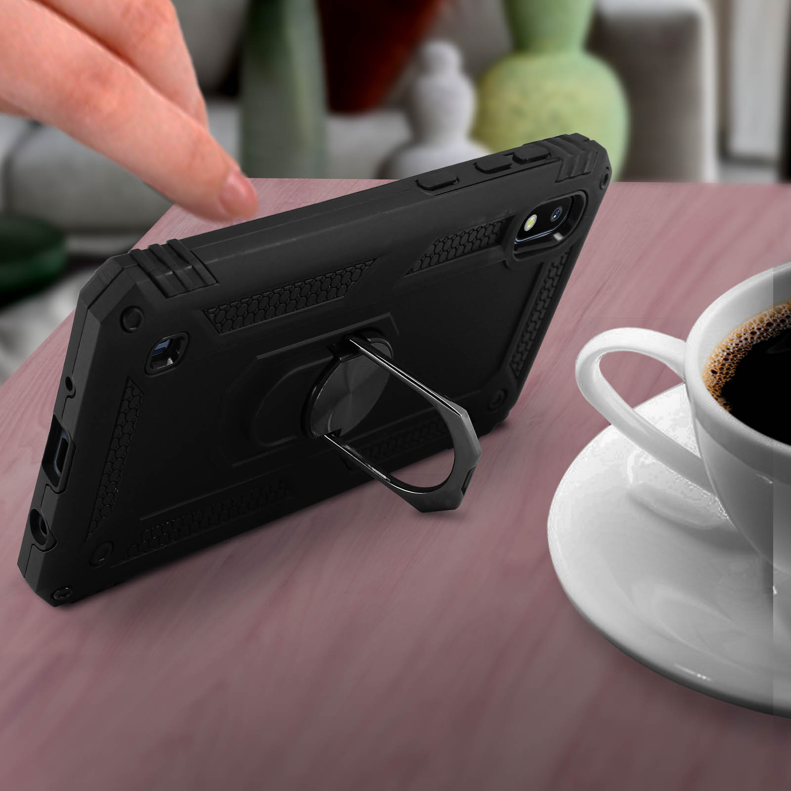 Téléphone noir avec anneau support. Une tasse de café à droite du téléphone.