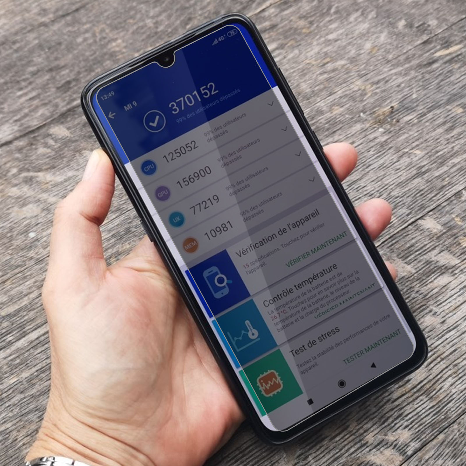 Una mano che tiene uno smartphone che mostra un risultato del test benchmark. Lo sfondo è una superficie di legno.