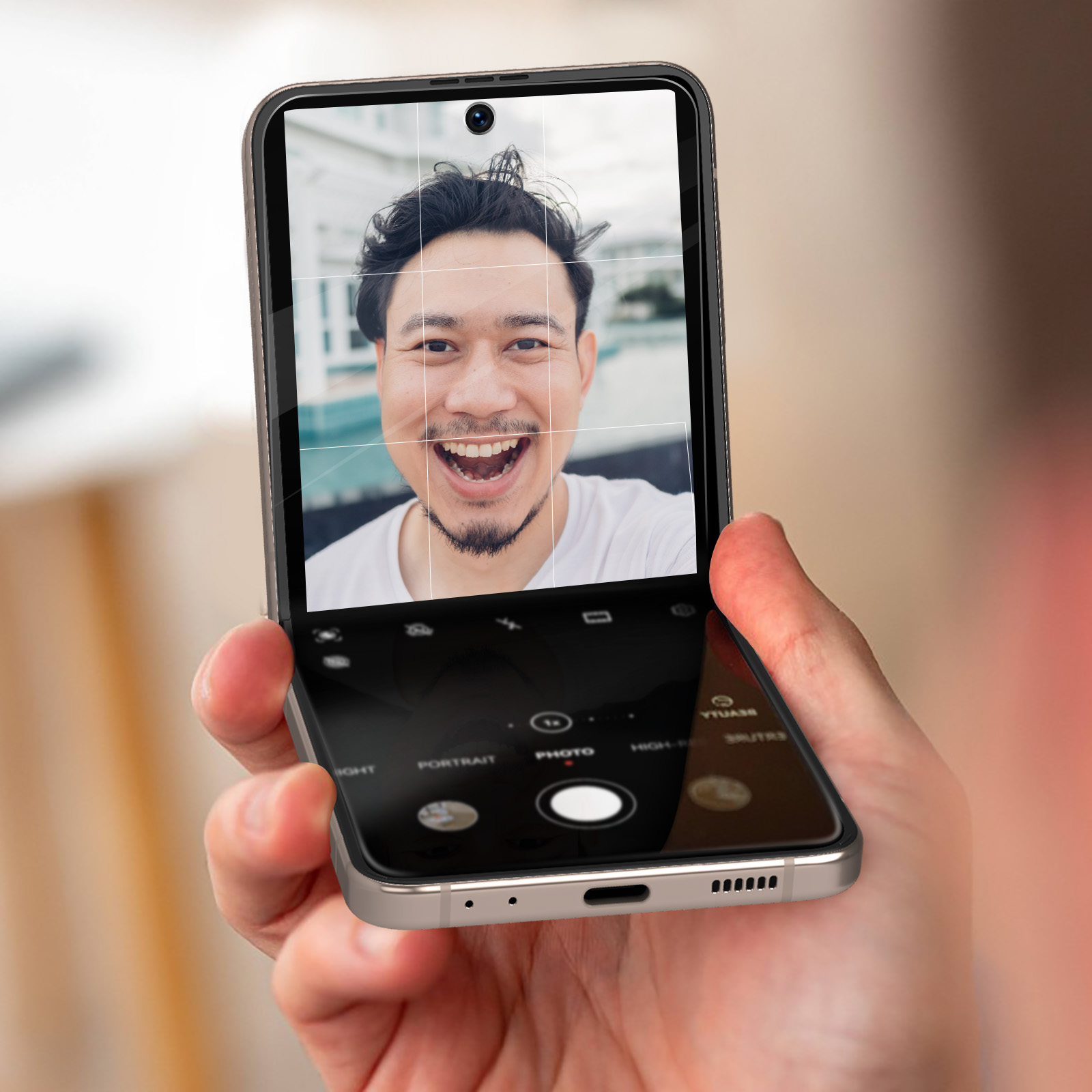 Un homme sourit à la caméra à travers l'écran du téléphone. Le téléphone est ouvert.