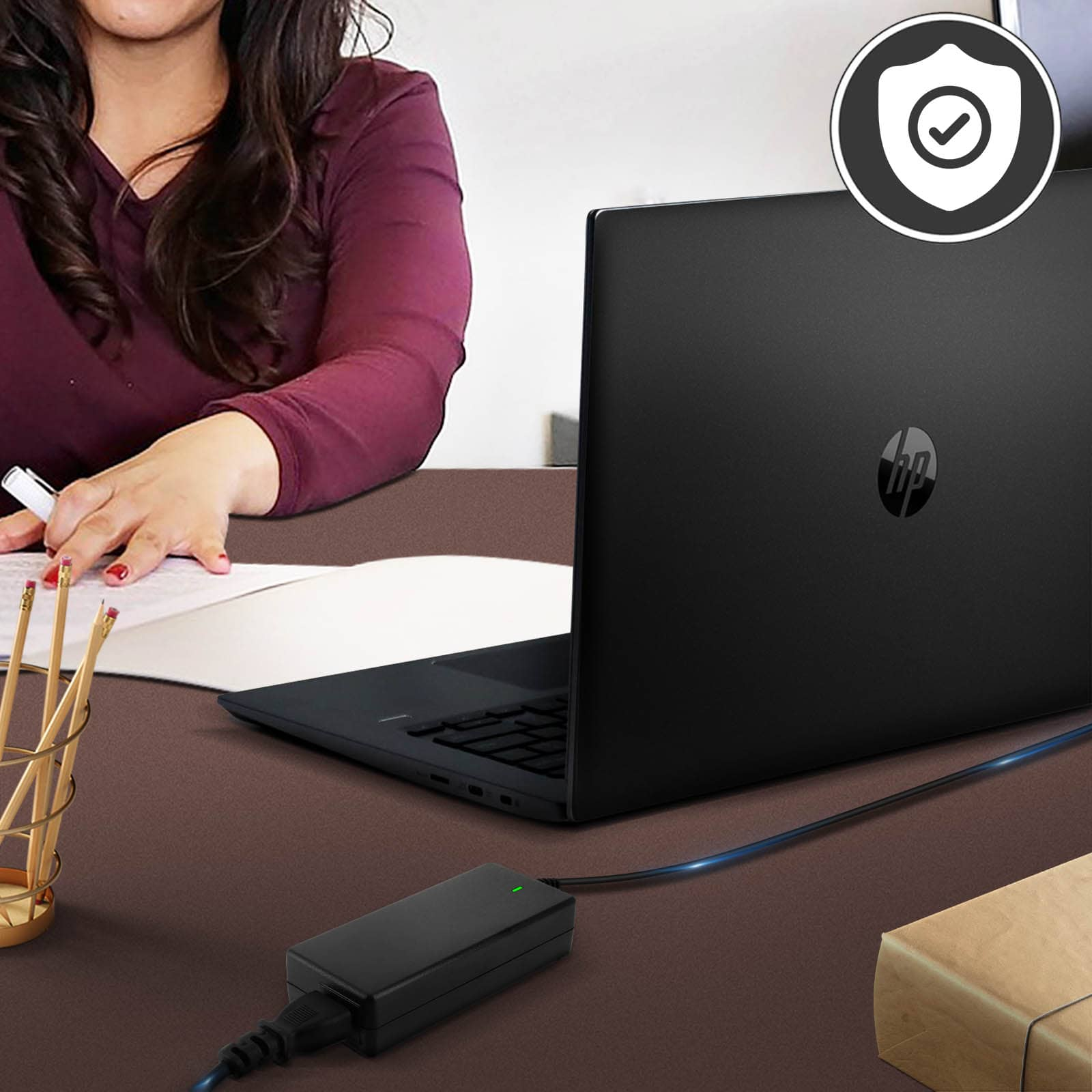 Mujer usando laptop negra. Adaptador enchufado en el escritorio.