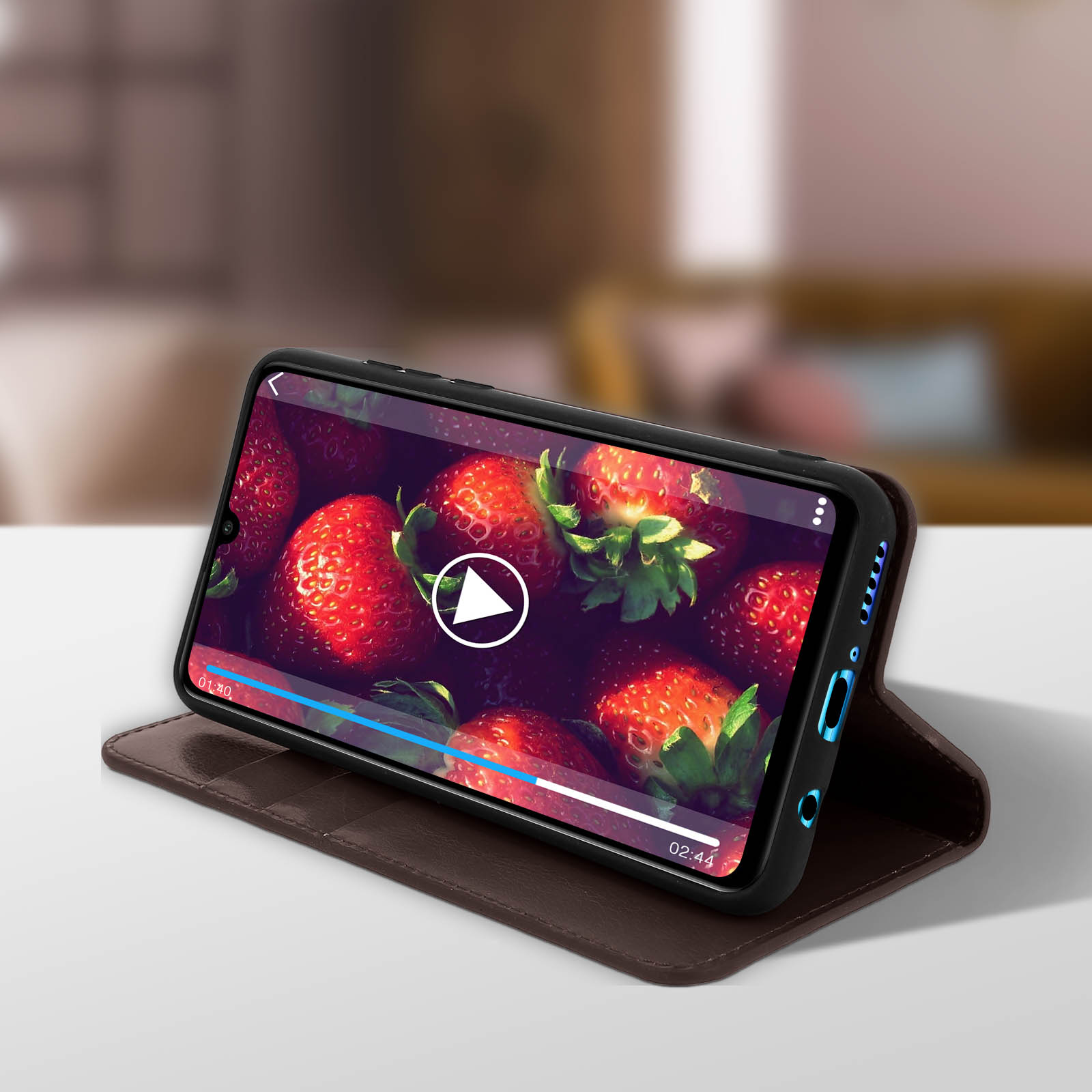 Un telefono mostra un video di fragole. Il telefono è in una custodia marrone ed è su un tavolo.