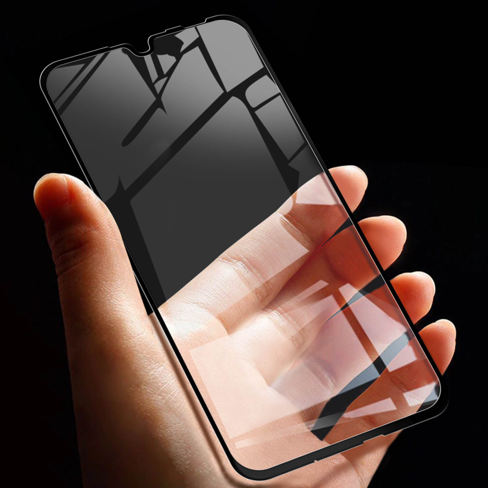 Mano che tiene telefono con protezione schermo, sfondo nero. La protezione schermo è trasparente.