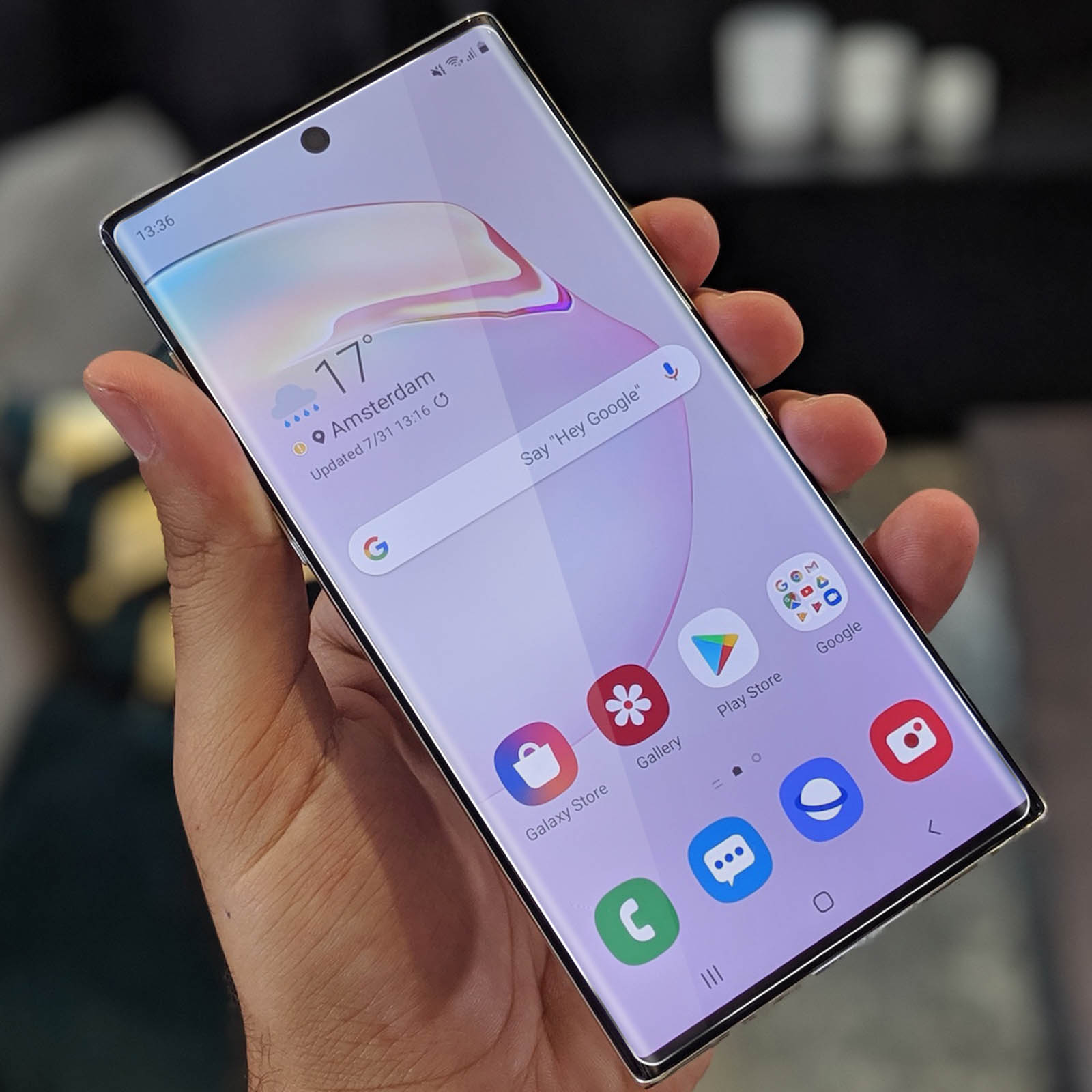 La mano di una persona che tiene un telefono acceso. Lo schermo mostra l'ora e le app.