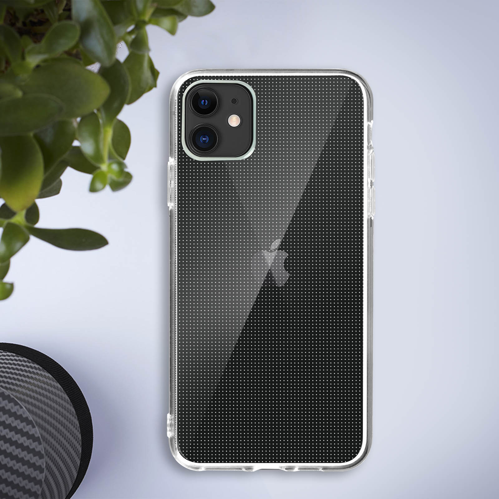 Transparante telefoonhoes met een stippenpatroon, op een licht oppervlak naast een plant.