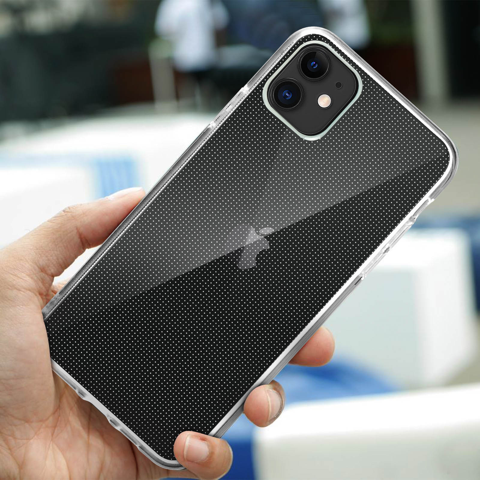 Une main tenant un téléphone dans une coque transparente avec des points blancs. Le téléphone est incliné.