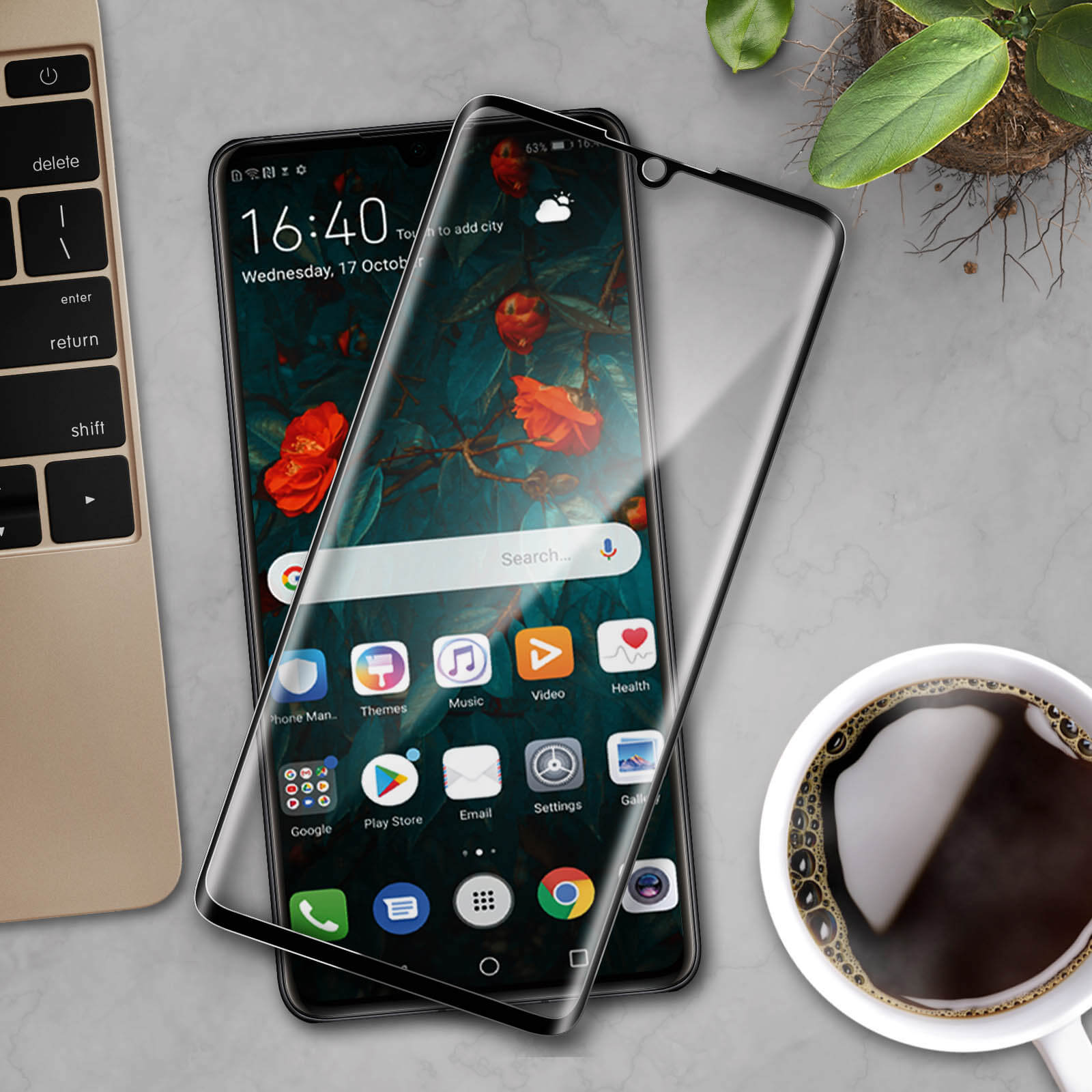 Un telefono con protezione schermo, una tazza di caffè e un laptop. Lo schermo mostra icone e una barra di ricerca.