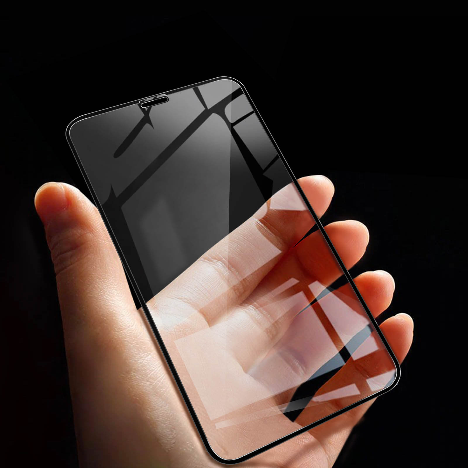 Mano che tiene un telefono con protezione schermo, sfondo nero.