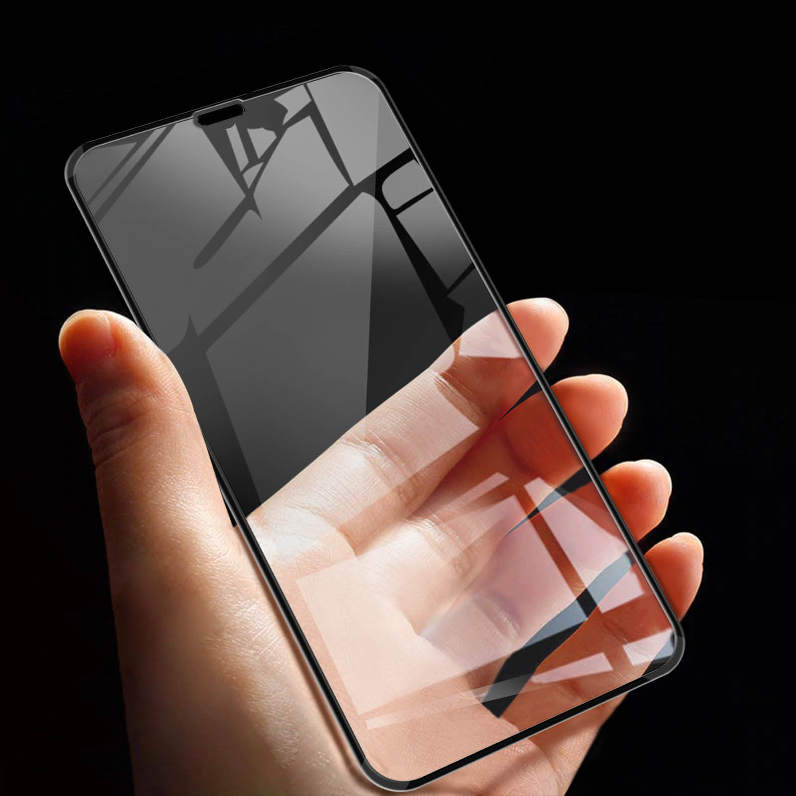 Una mano che tiene uno smartphone con una protezione per lo schermo. Sfondo nero che riflette il telefono.