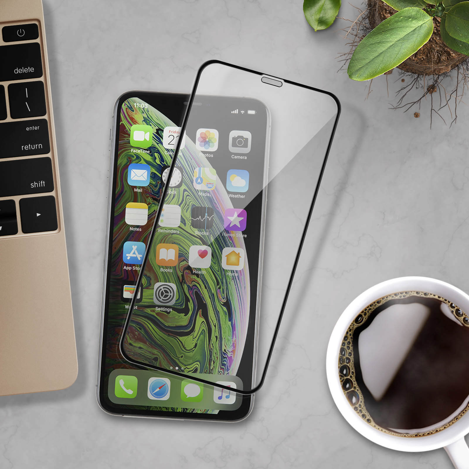 Un telefono con protezione schermo, una tazza di caffè e un laptop. Lo schermo mostra un orologio e icone.