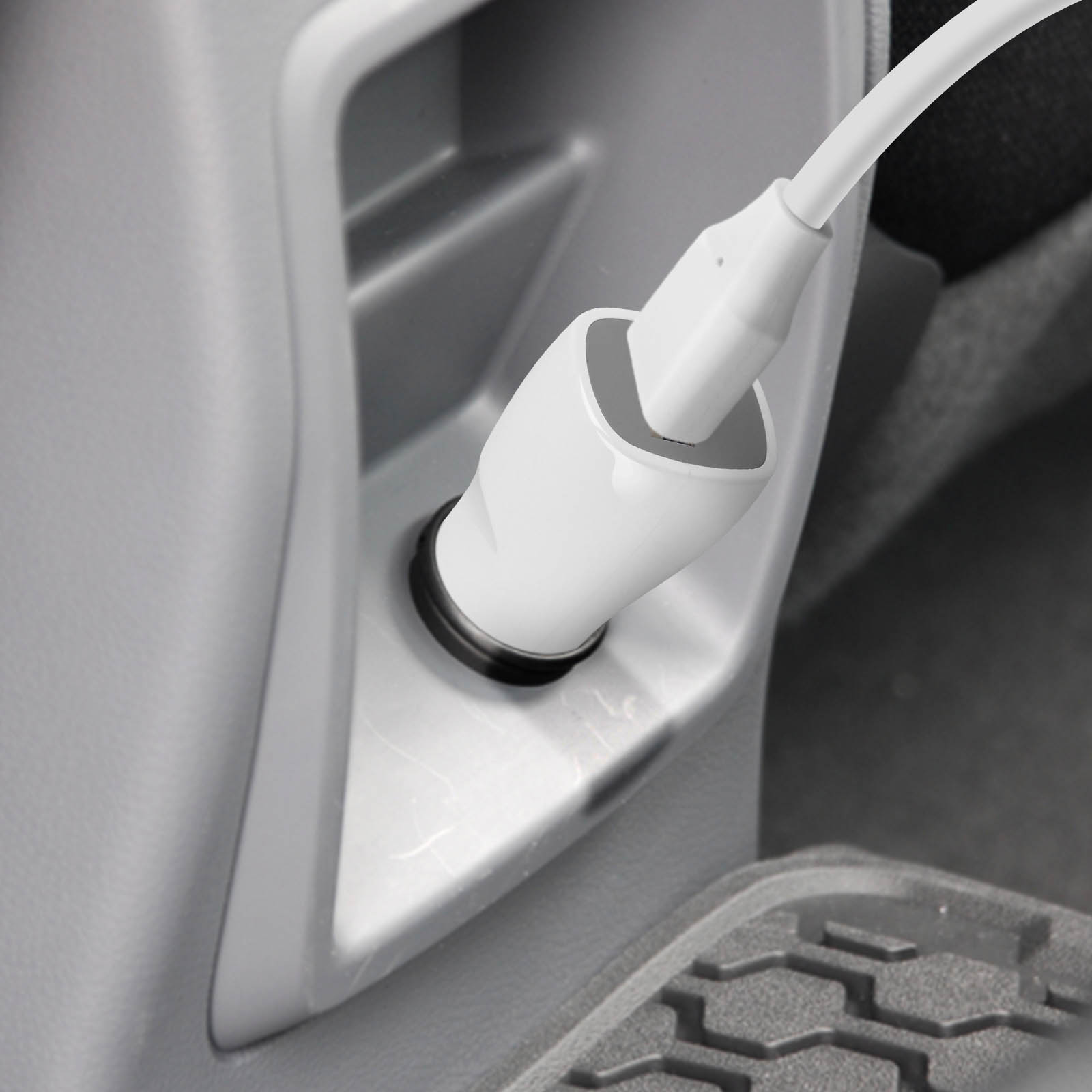 Weißes Autoladegerät, das in eine Steckdose im Auto eingesteckt ist. Der Hintergrund ist ein grauer Innenraum.
