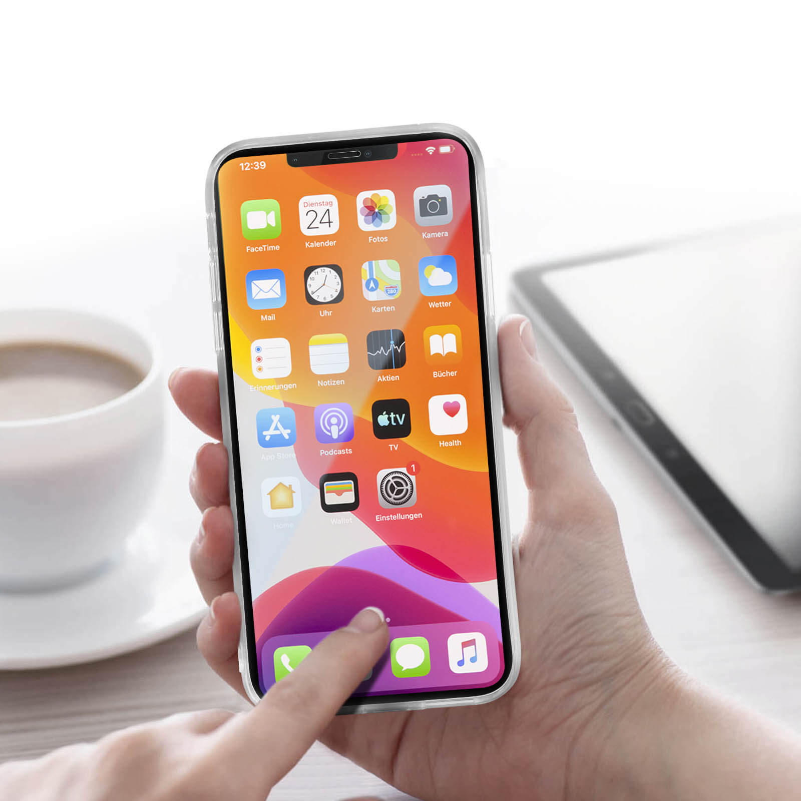 Hand hält Telefon mit bunten App-Symbolen. Kaffeetasse und Tablet in der Nähe.