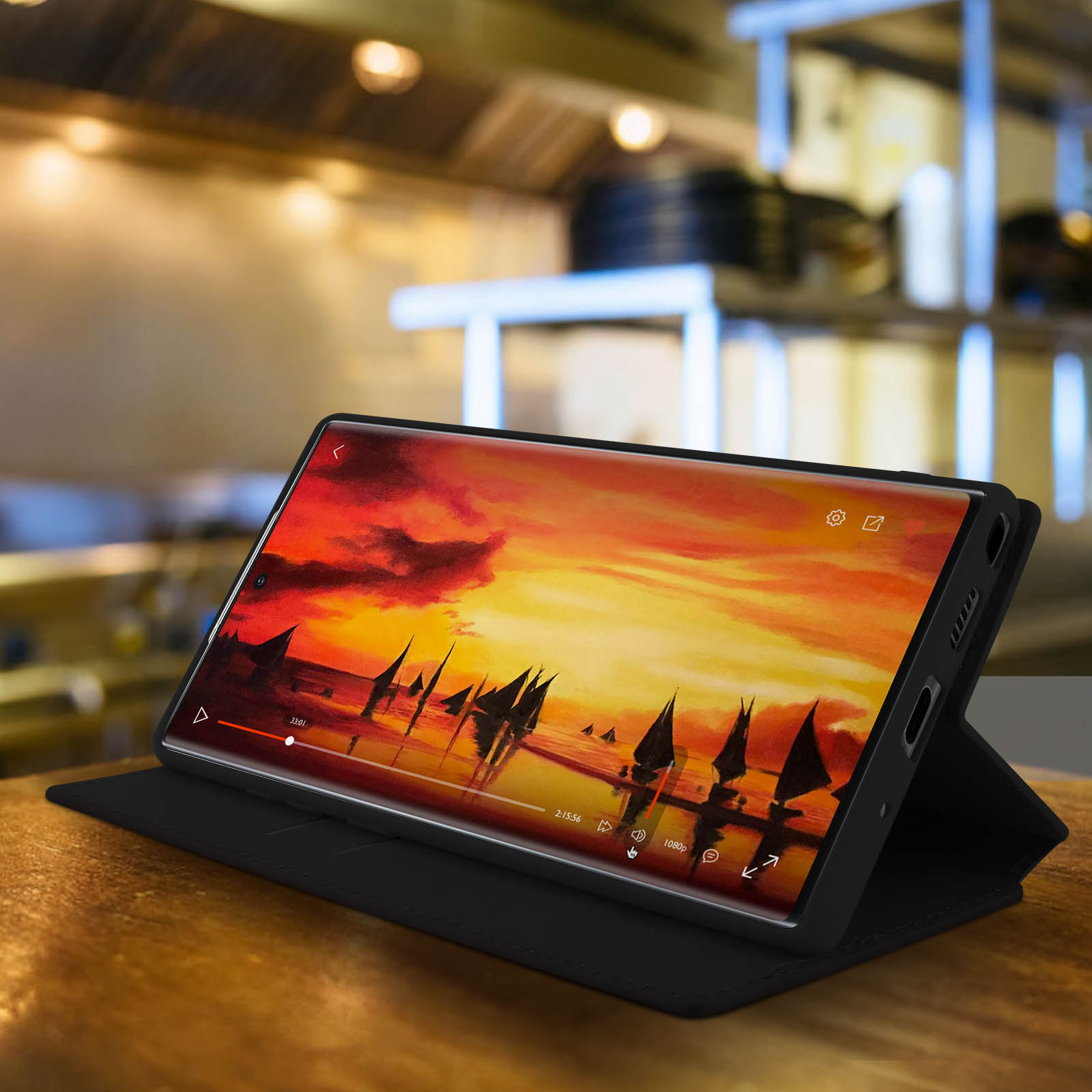 Tablette sur une table avec scène de coucher de soleil à l'écran, dans un étui noir.
