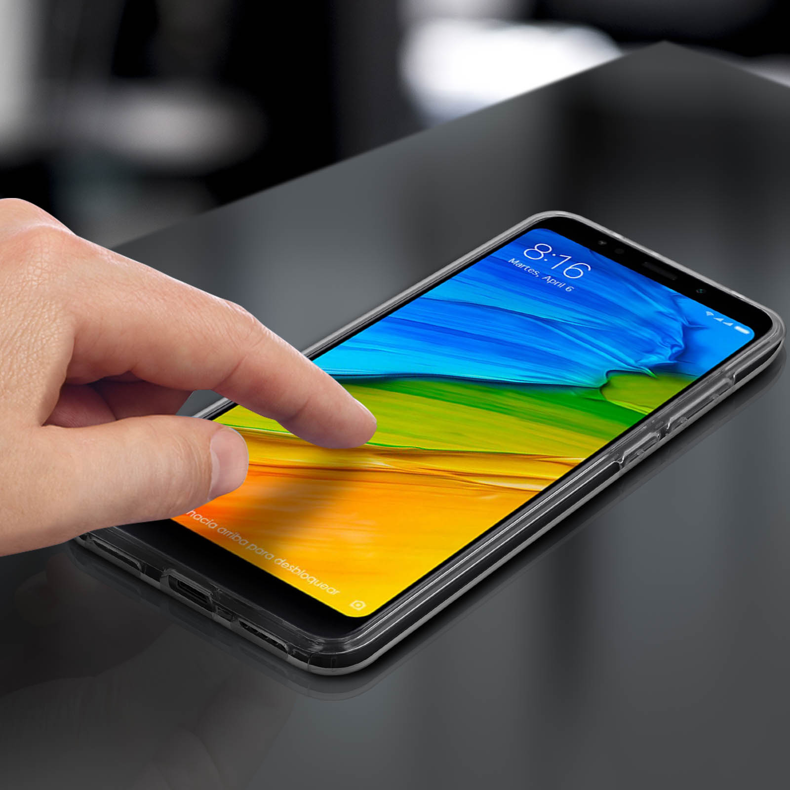 Una mano toca la pantalla de un teléfono. La pantalla muestra un fondo colorido.
