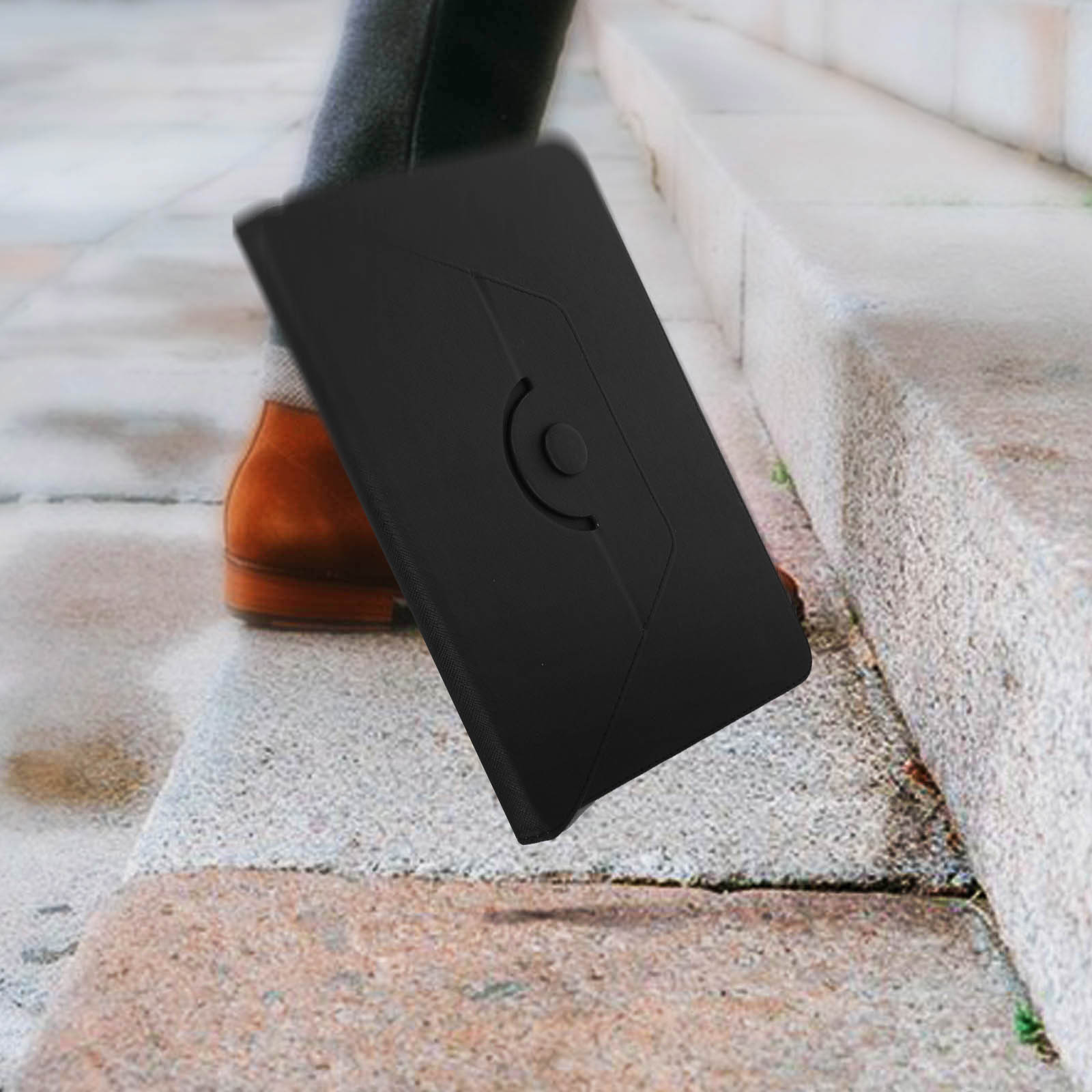 Un piede di una persona calpesta una custodia per telefono nera su una serie di gradini.