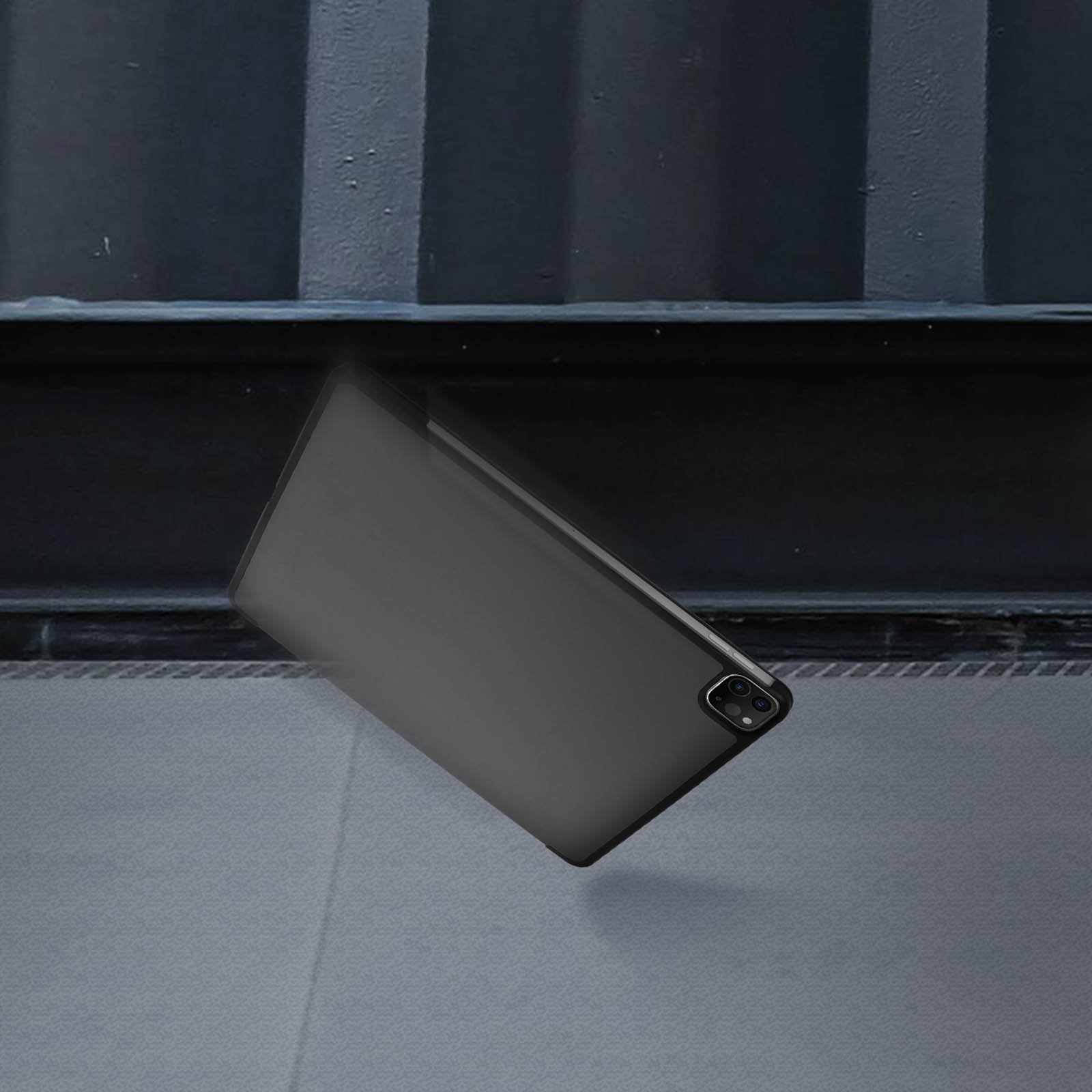 Eine schwarze Tablet-Hülle, die auf eine graue Oberfläche in der Nähe einer dunklen Struktur fällt.