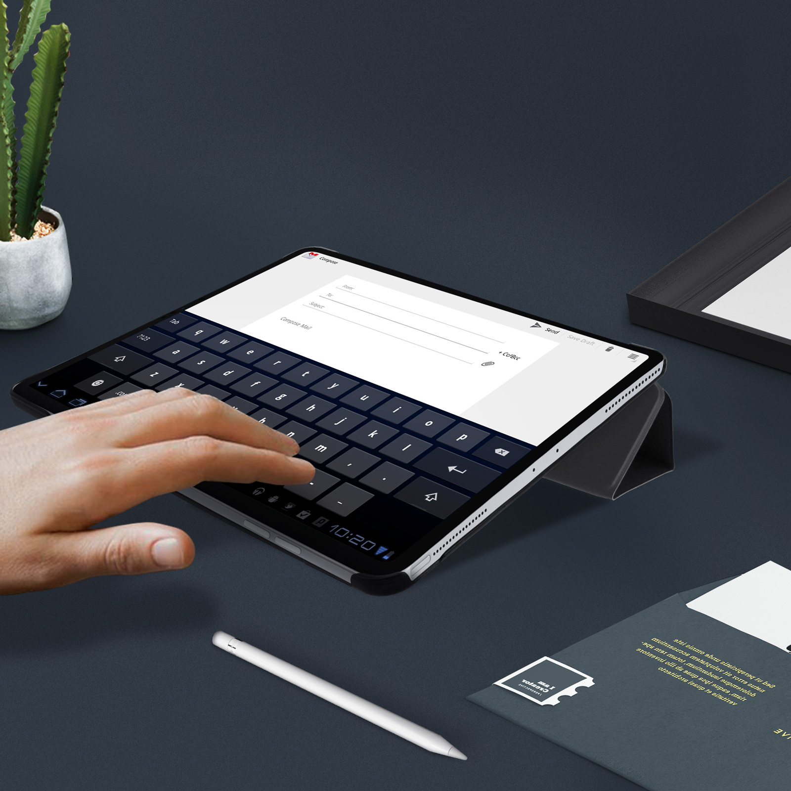 Tablet mit Tastatur auf dem Tisch. Hand tippt. Stift und Papier in der Nähe.
