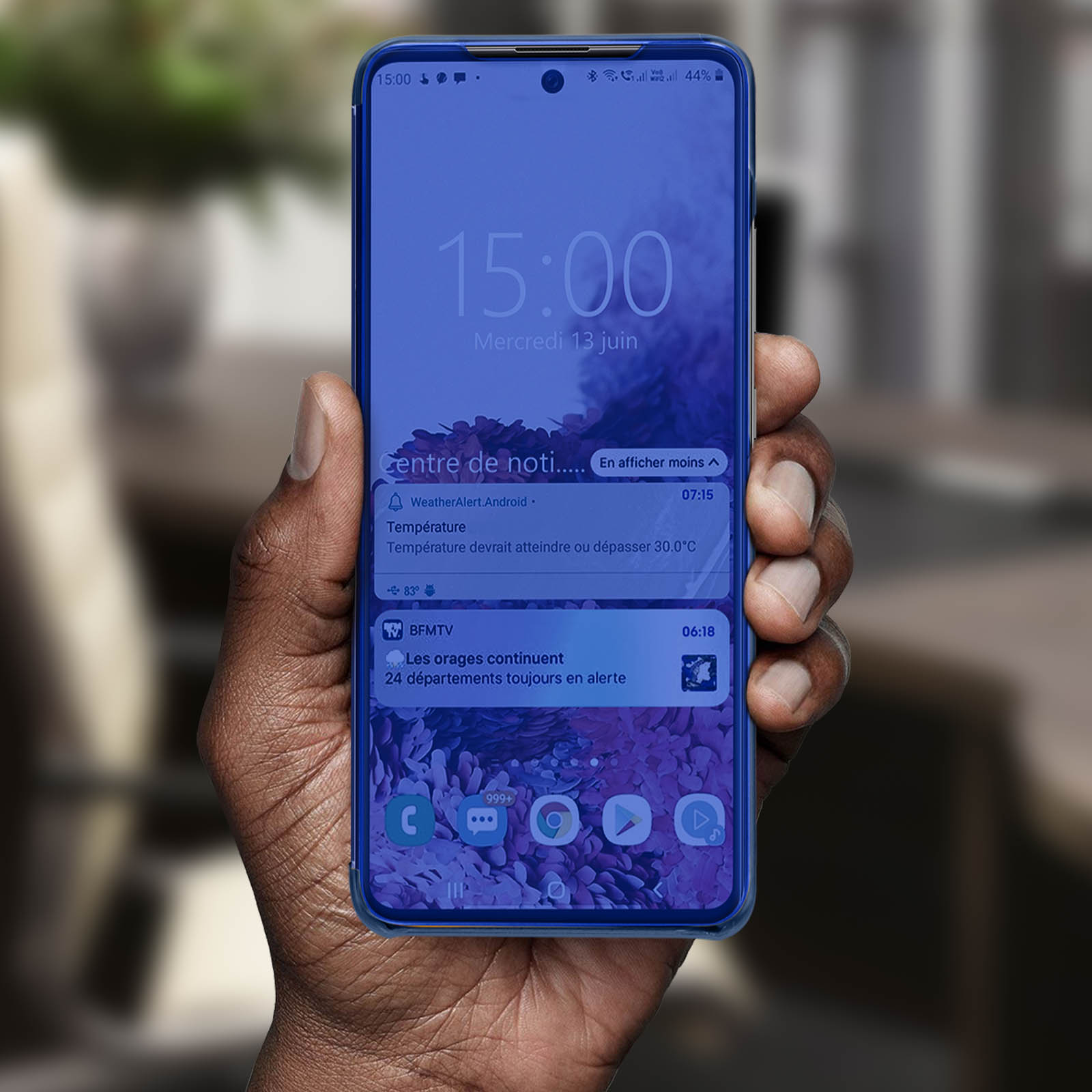 Una mano tiene un telefono che mostra notifiche con uno schermo blu.