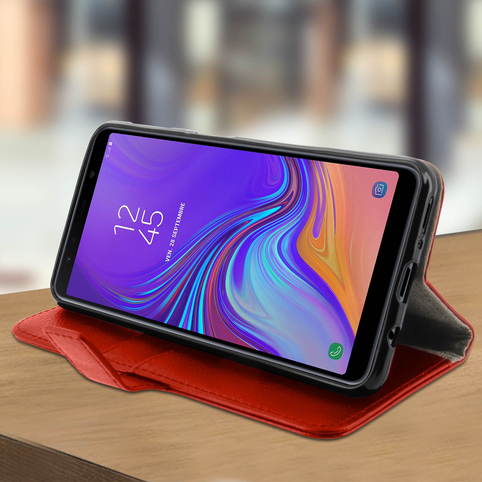 Telefono in una custodia rossa aperta su un tavolo di legno. Lo schermo mostra un'interfaccia colorata.