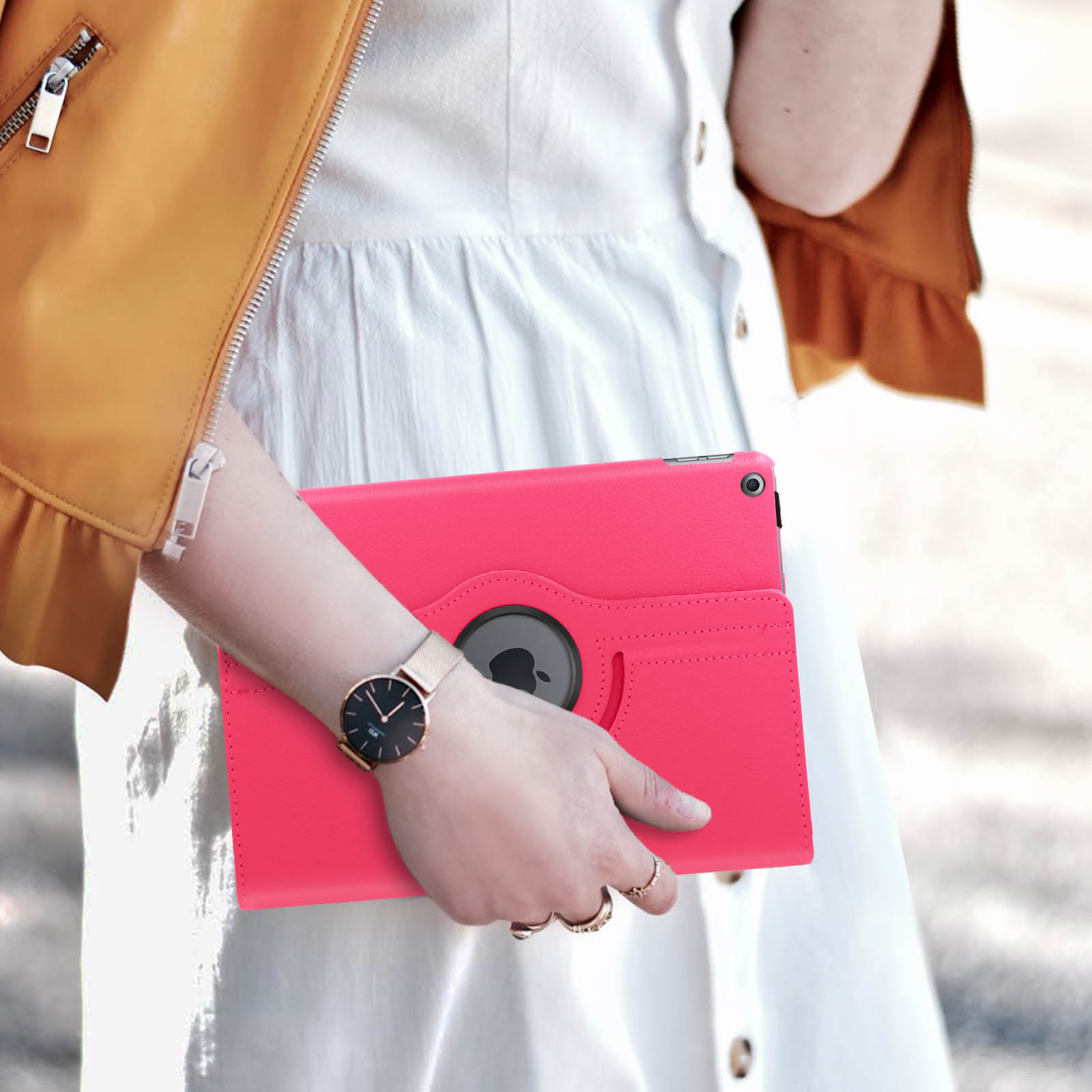 Una donna che tiene una custodia rosa per iPad con un orologio e anelli.