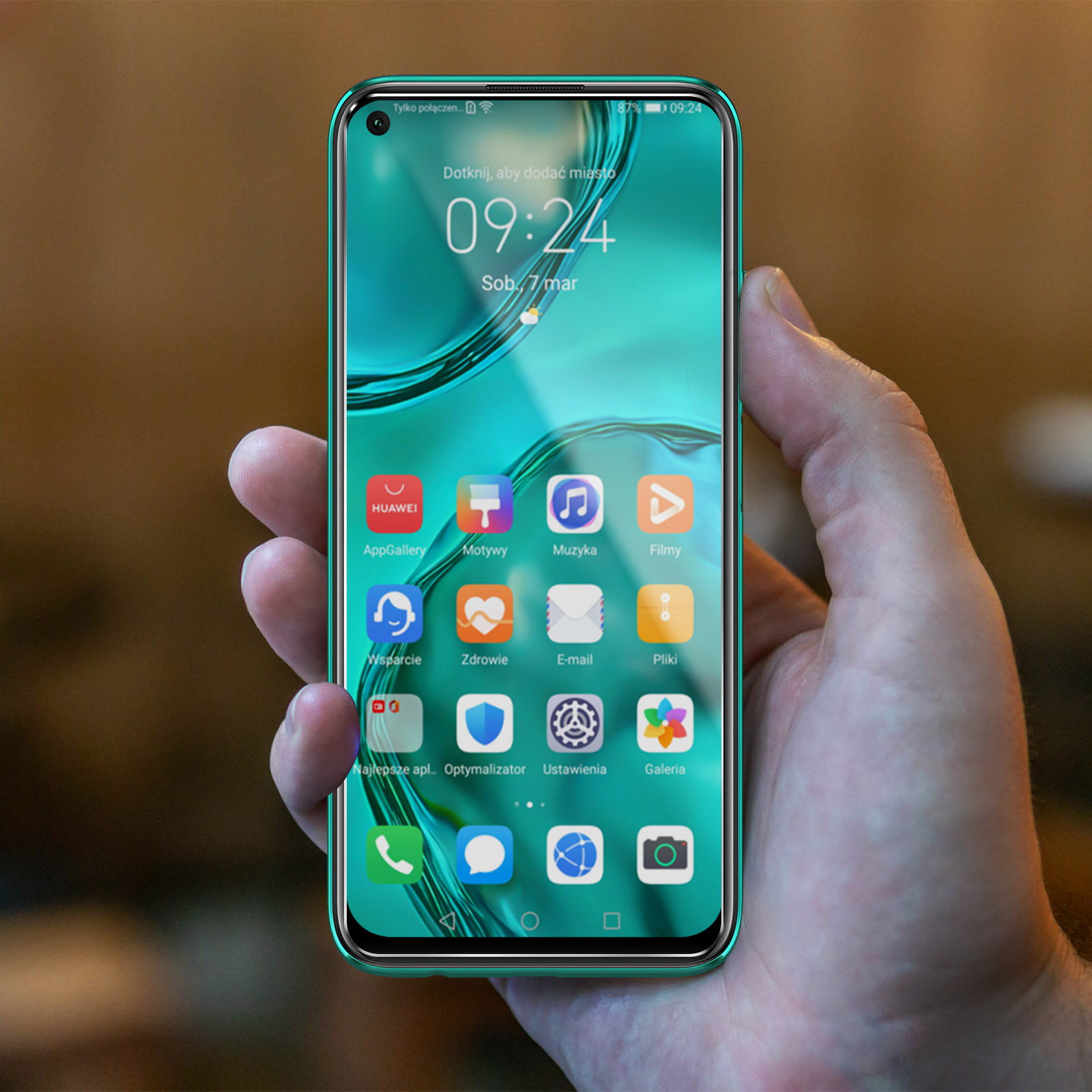 Una mano che tiene un telefono verde. Lo schermo mostra un'interfaccia turchese con icone di app, tra cui Huawei, galleria e impostazioni.