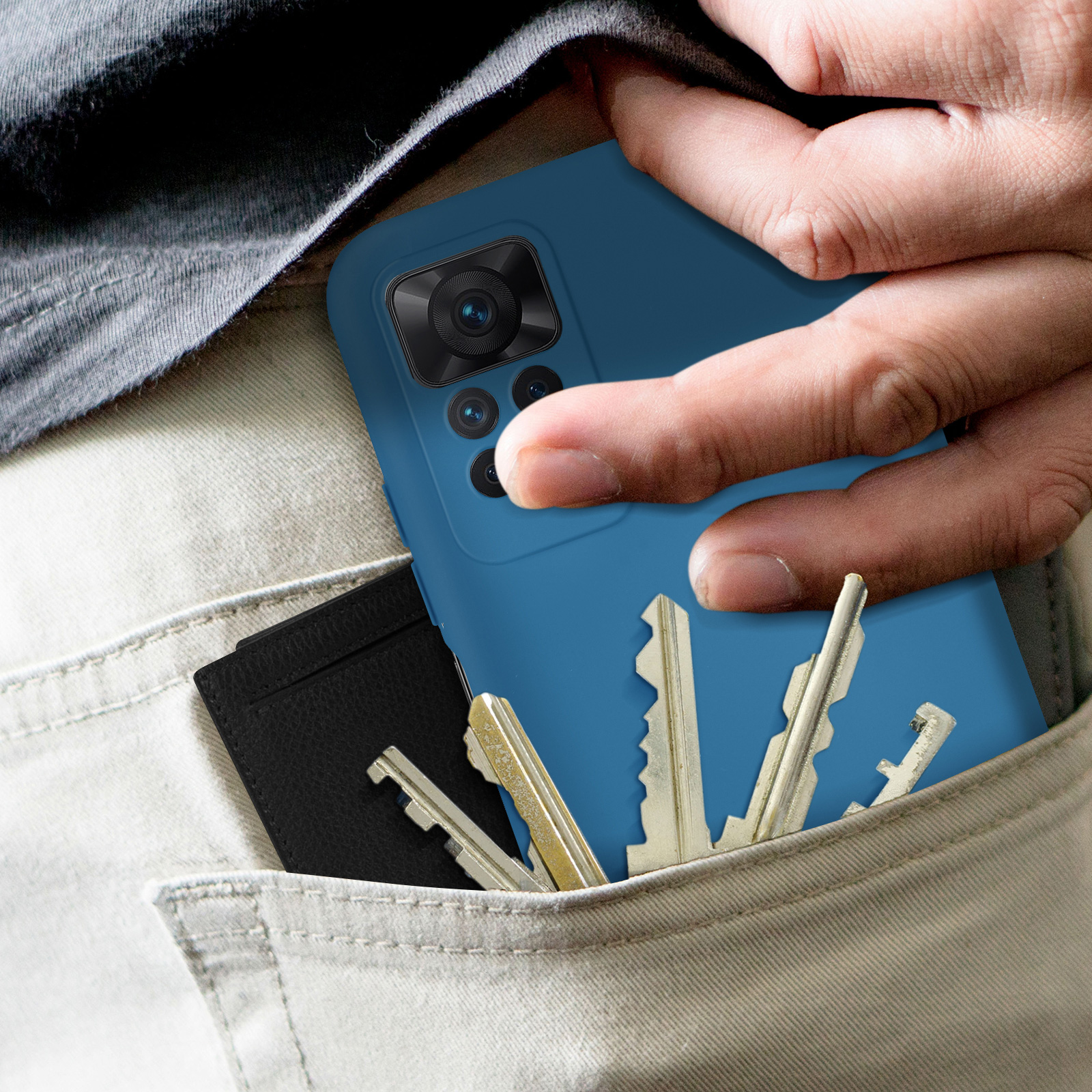 Een hand die een blauwe telefoon vasthoudt met een hoesje, sleutels en een portemonnee in een zak.