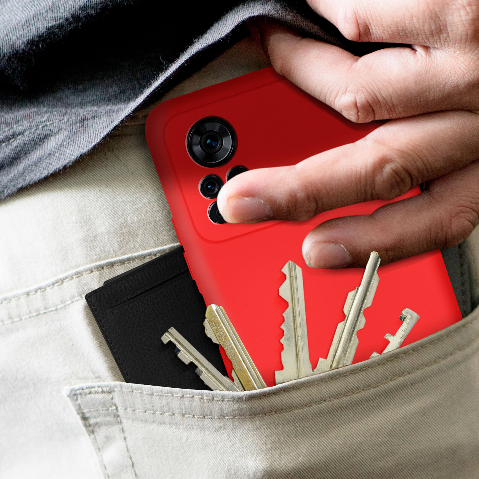 Mano in tasca con telefono rosso, chiavi e porta carte nero.