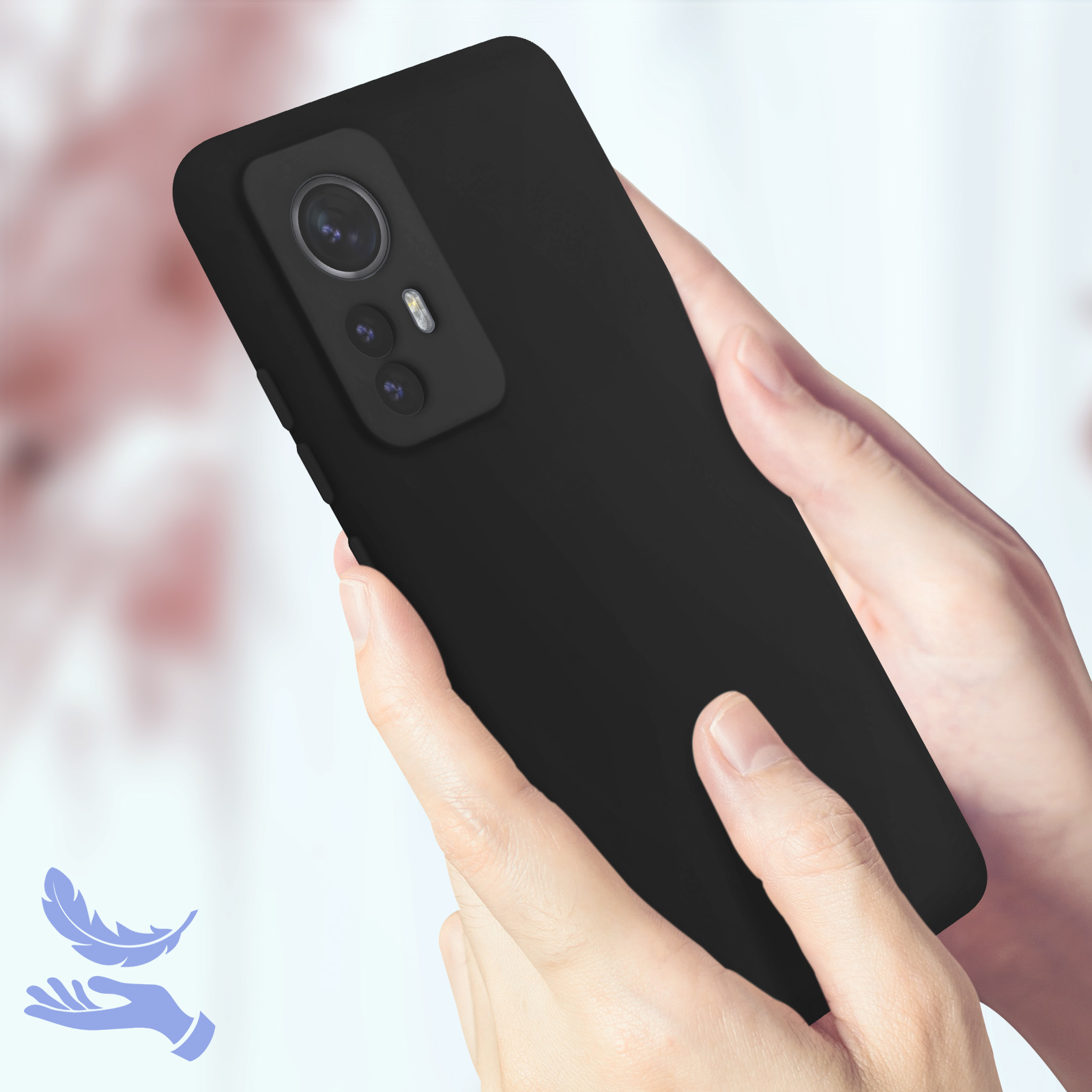 Mani che tengono un telefono nero con tripla fotocamera su sfondo sfocato.