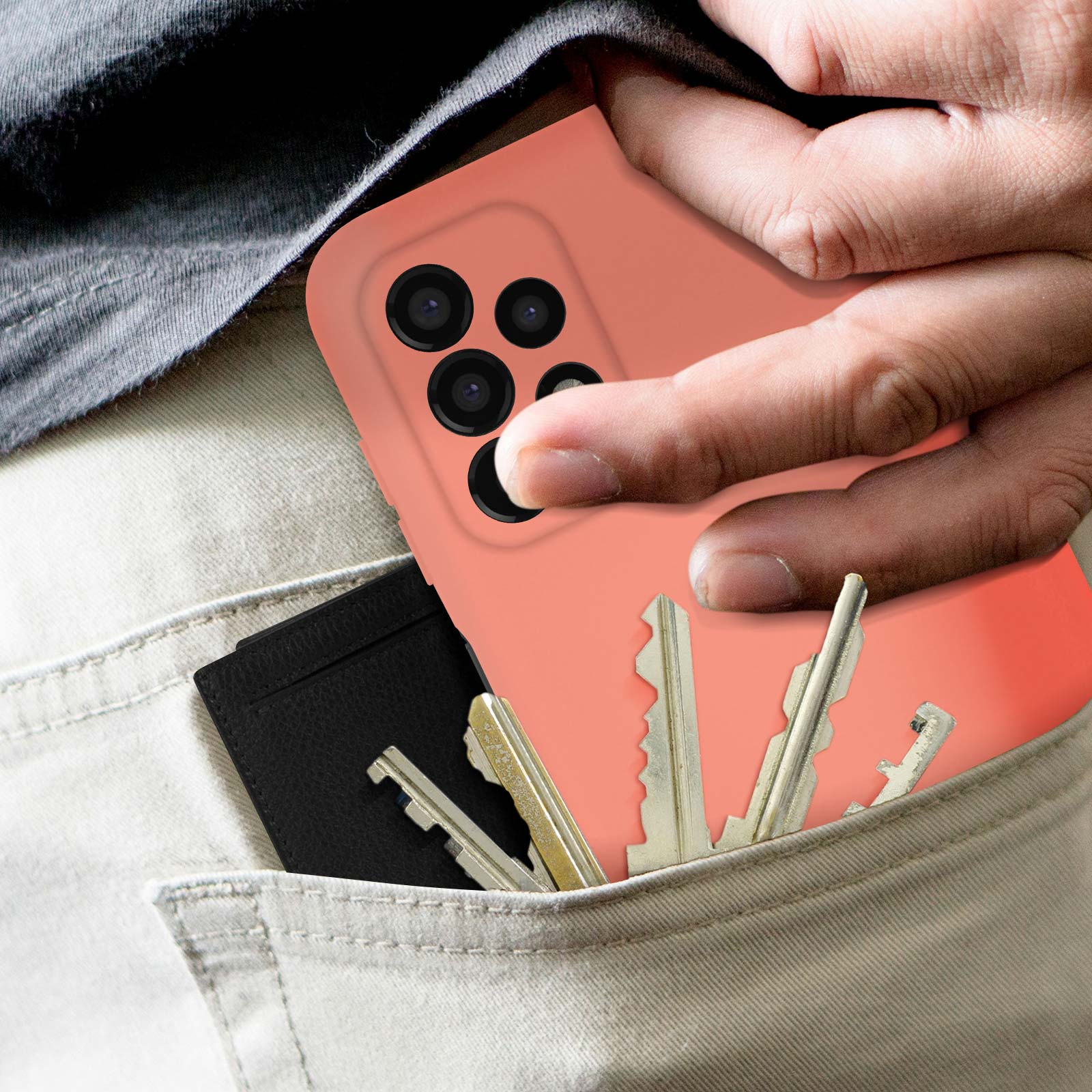 Hand die een telefoon met koraalroze hoes vasthoudt. Sleutels en portemonnee in zak.
