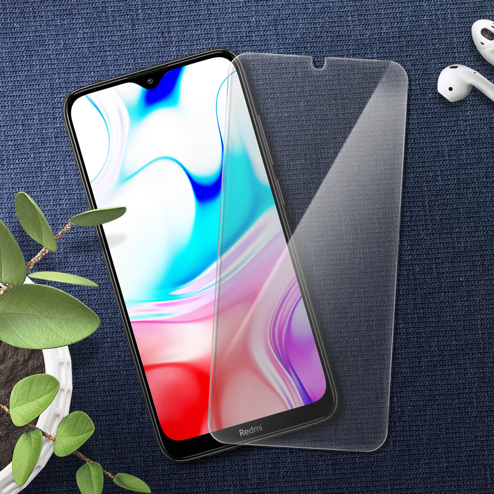 Smartphone scherm en protector. Telefoon ligt op een blauw oppervlak met bladeren en oortelefoons.