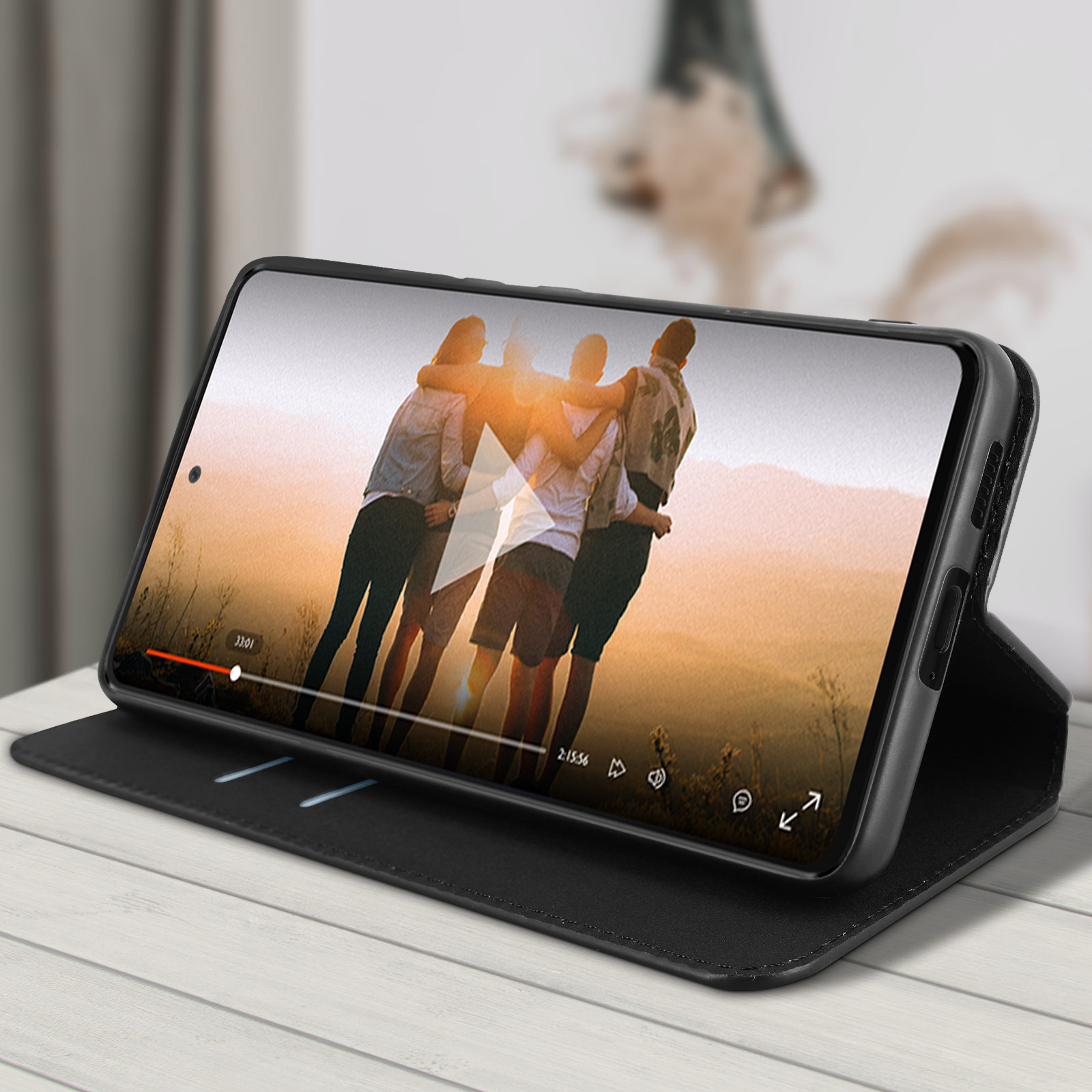 Telefoon in een folio hoes die een video van mensen afspeelt. De hoes ligt op een witte tafel.