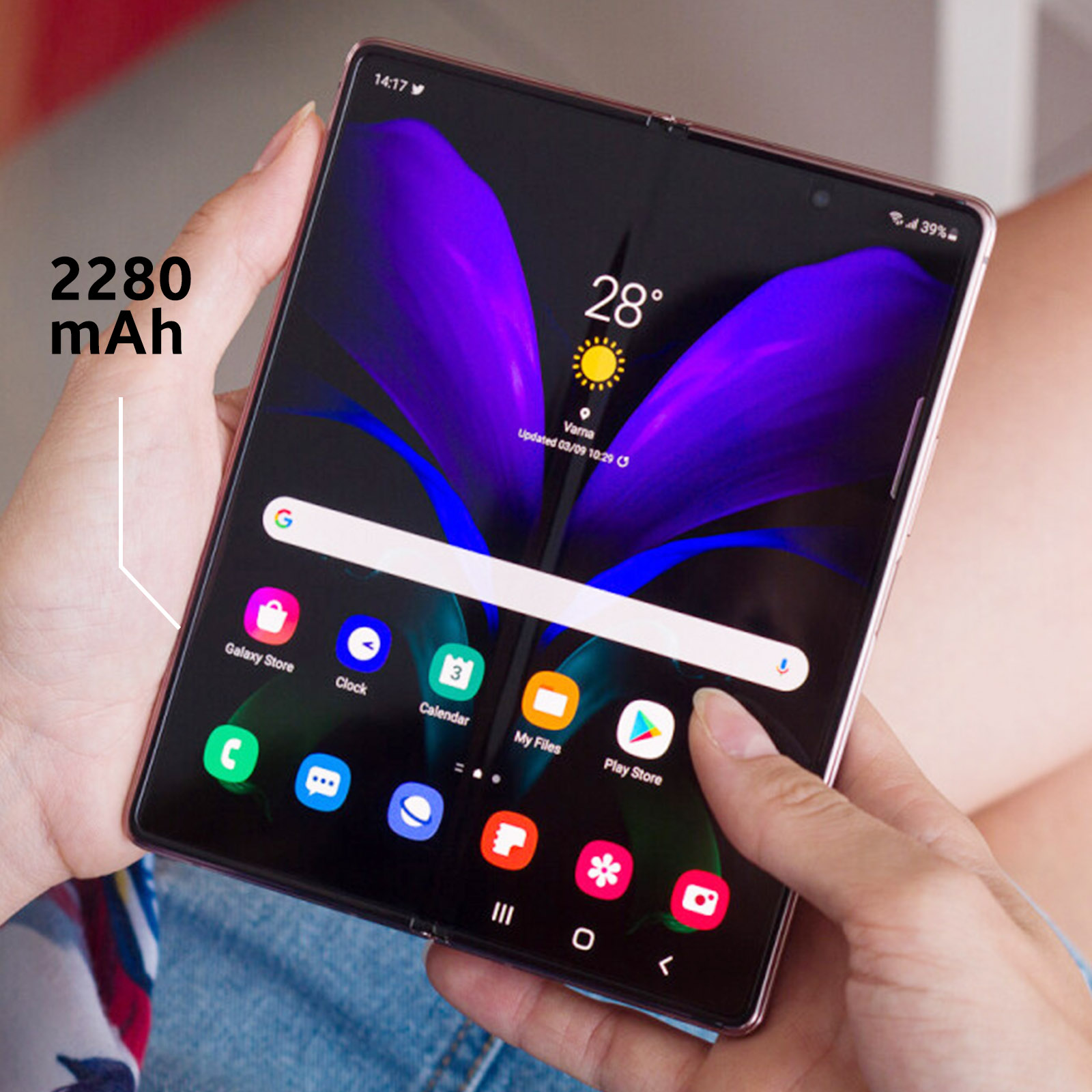 Mains tenant un téléphone plié avec écran coloré montrant des applications et l'heure.